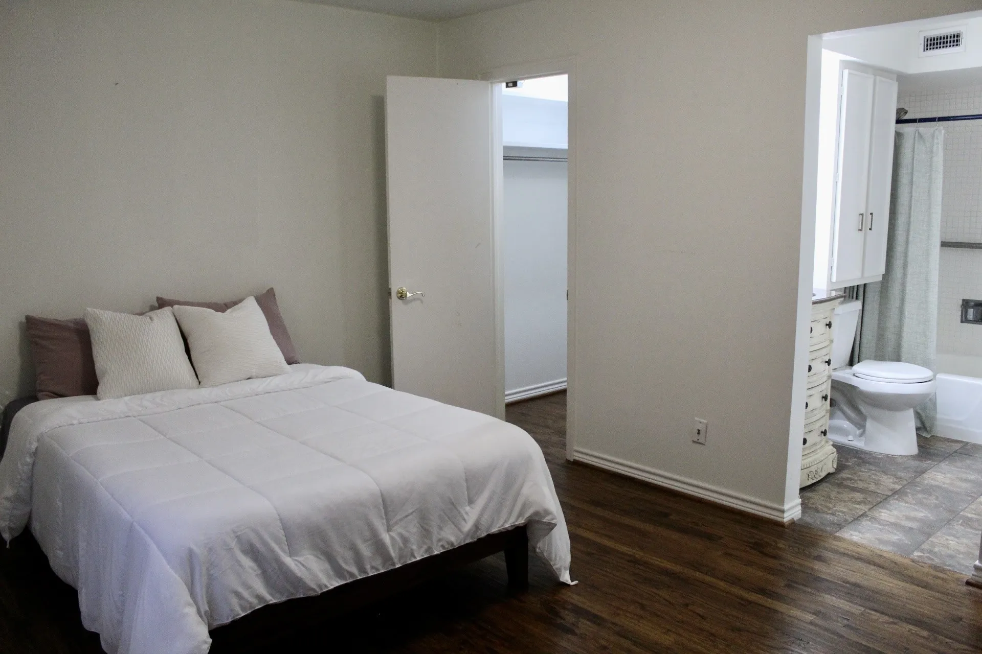 Bedroom with a walk in closet, dark wood-type flooring, and ensuite bath