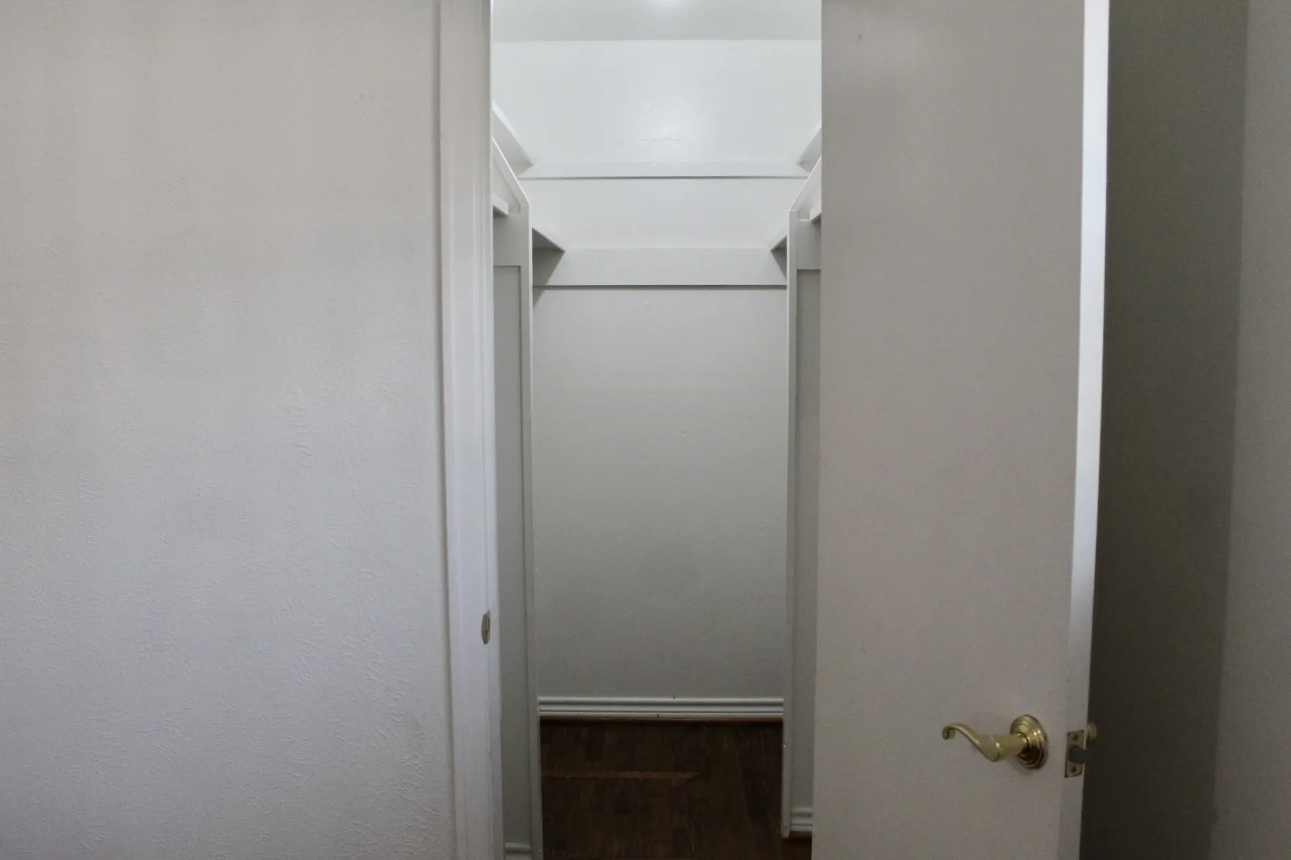 Walk in closet with dark wood-style flooring