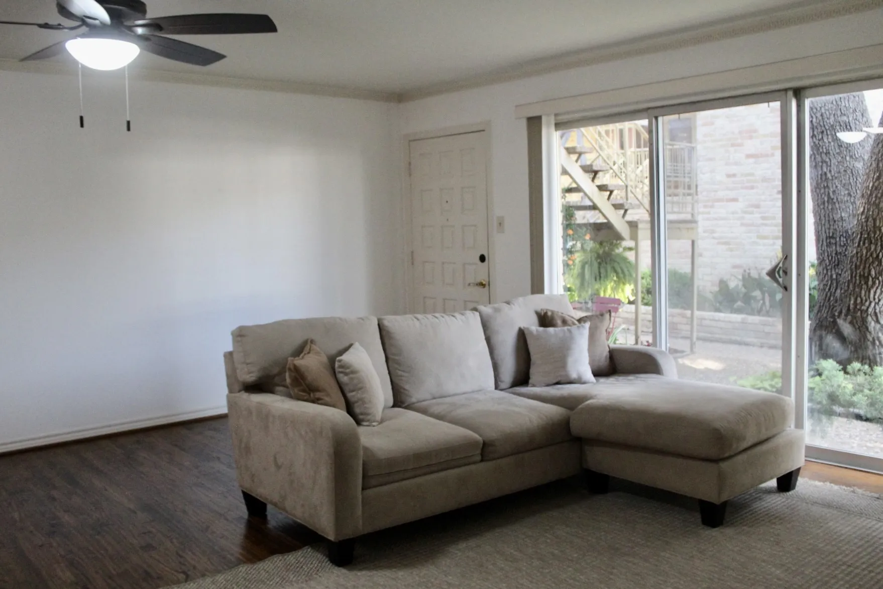Living room featuring wood finished floors, crown molding, ceiling fan, and stairs
