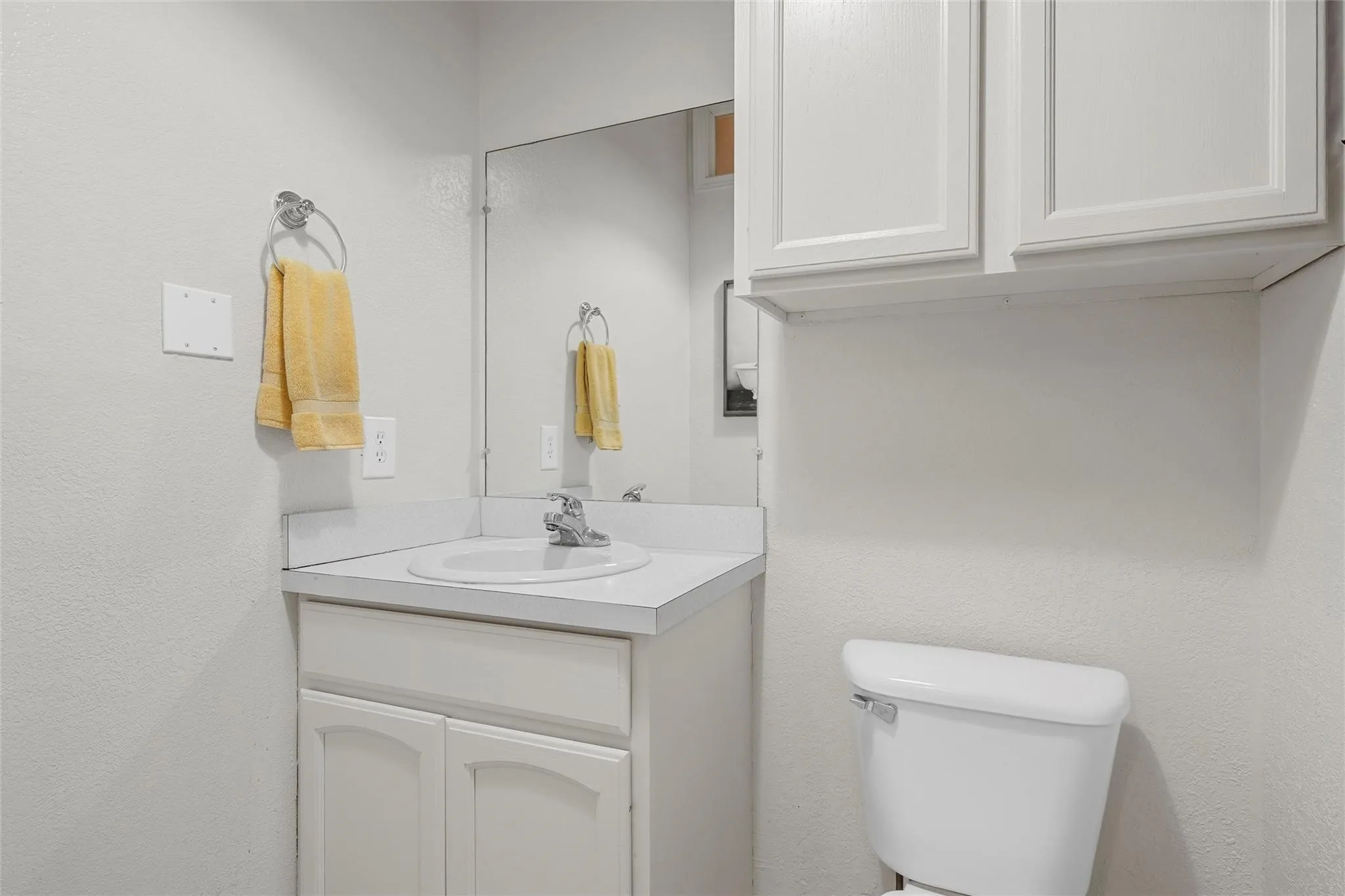 Half bath featuring vanity and a textured wall