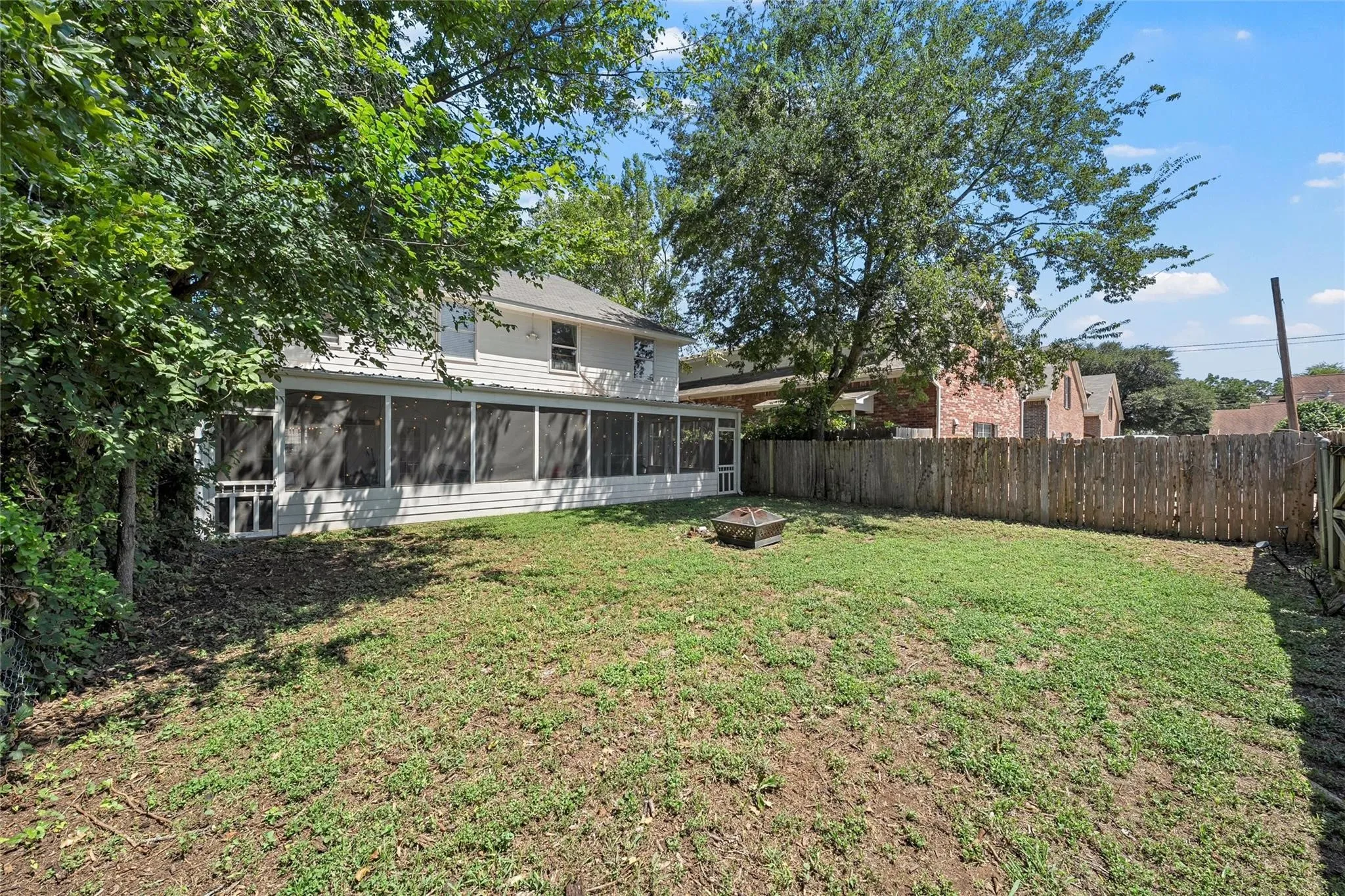 Fenced backyard featuring a fire pit and a sunroom