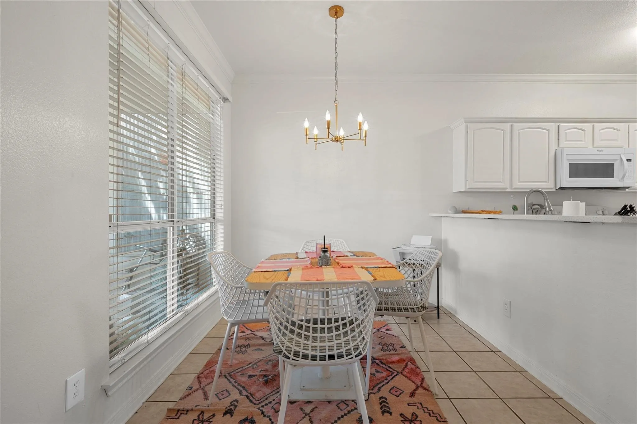 Dining area featuring light tile patterned floors, ornamental molding, and a chandelier