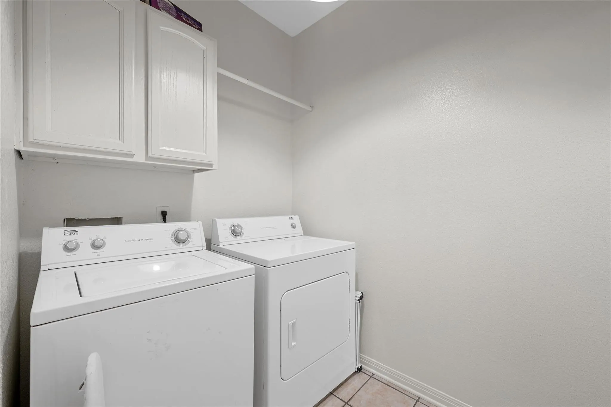 Washroom featuring light tile patterned floors, cabinet space, and separate washer and dryer