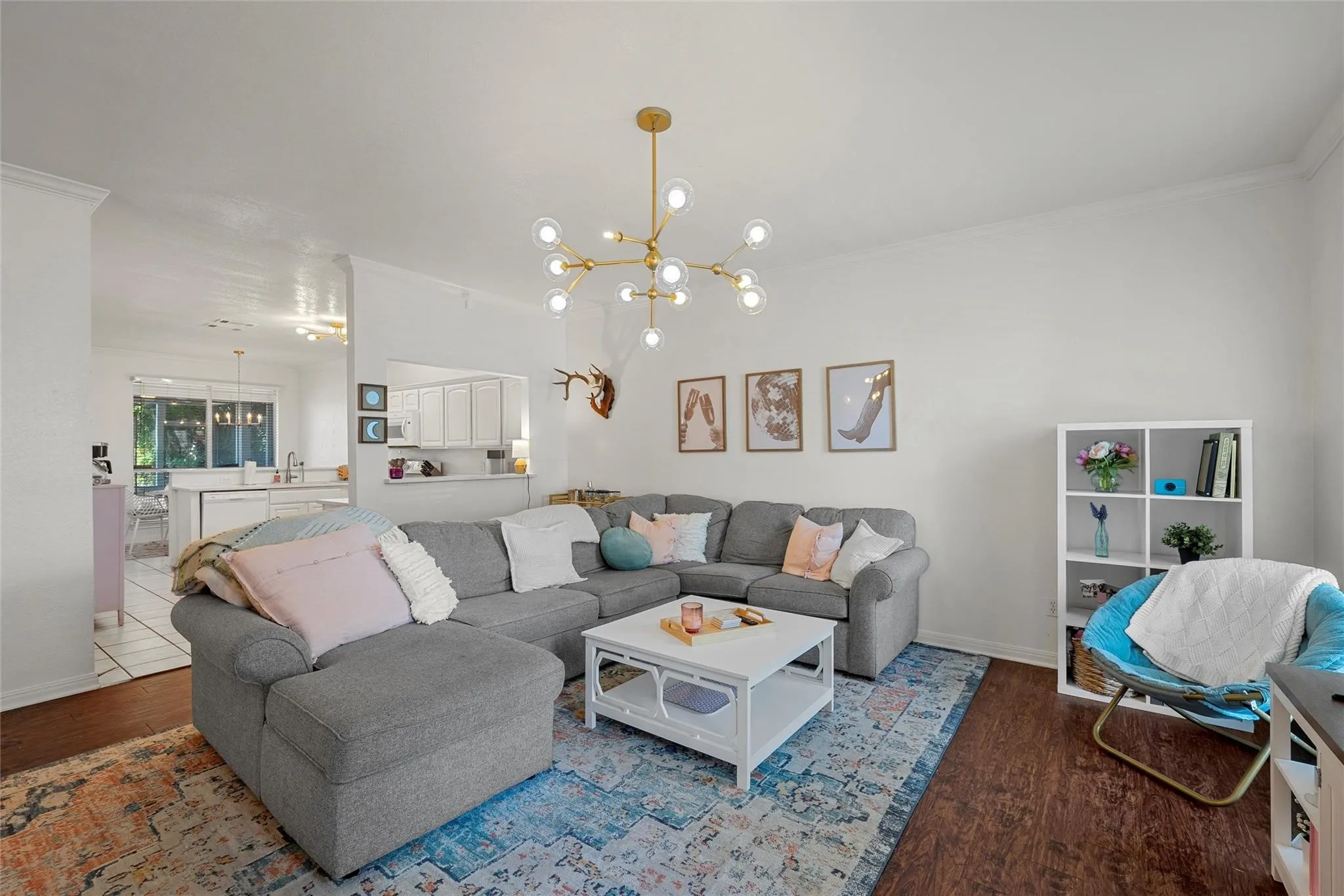 Living area featuring a chandelier, ornamental molding, and dark wood-style floors
