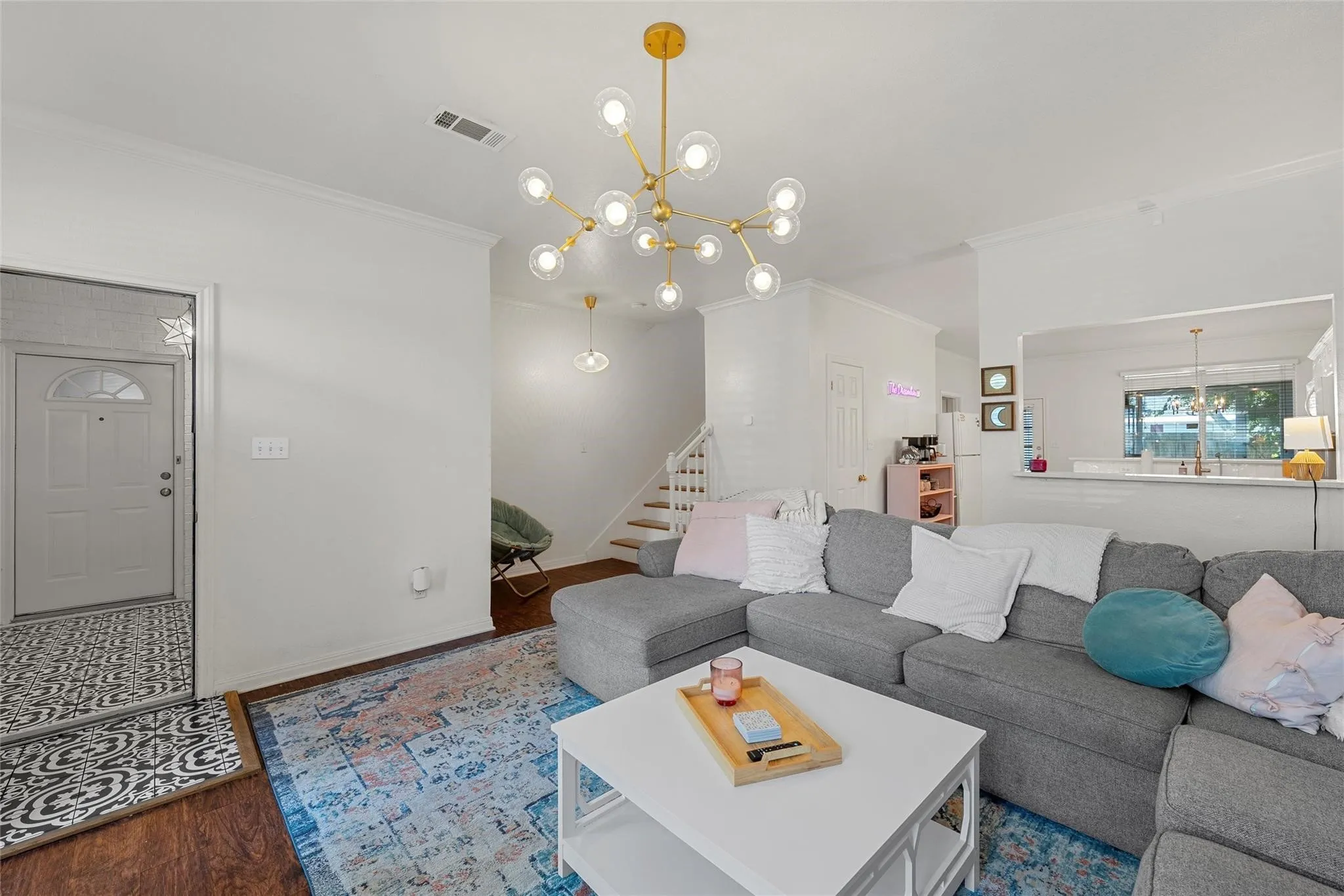 Living area with ornamental molding, stairway, a chandelier, and wood finished floors