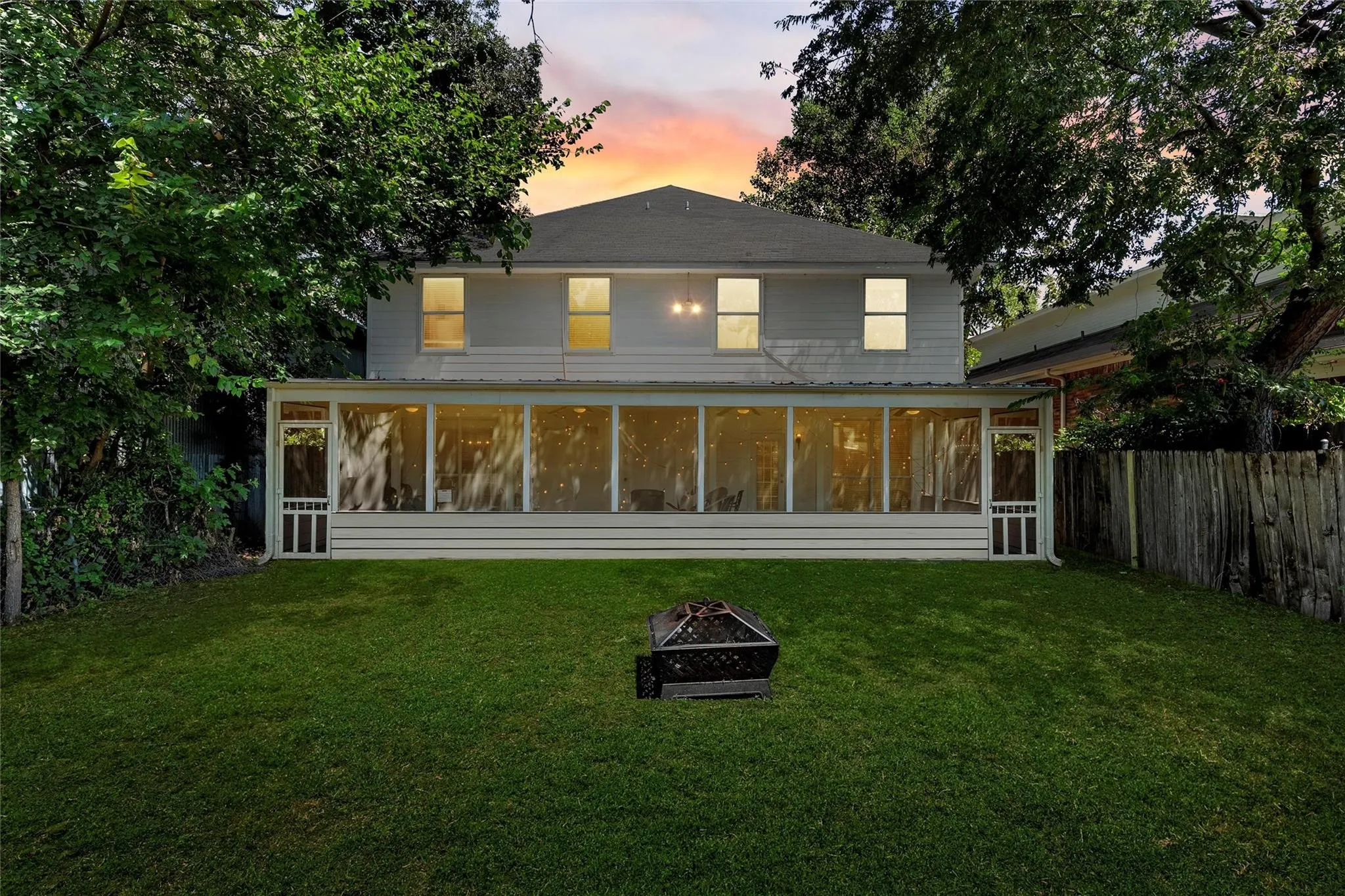 Back of house with an outdoor fire pit, a sunroom, and a yard