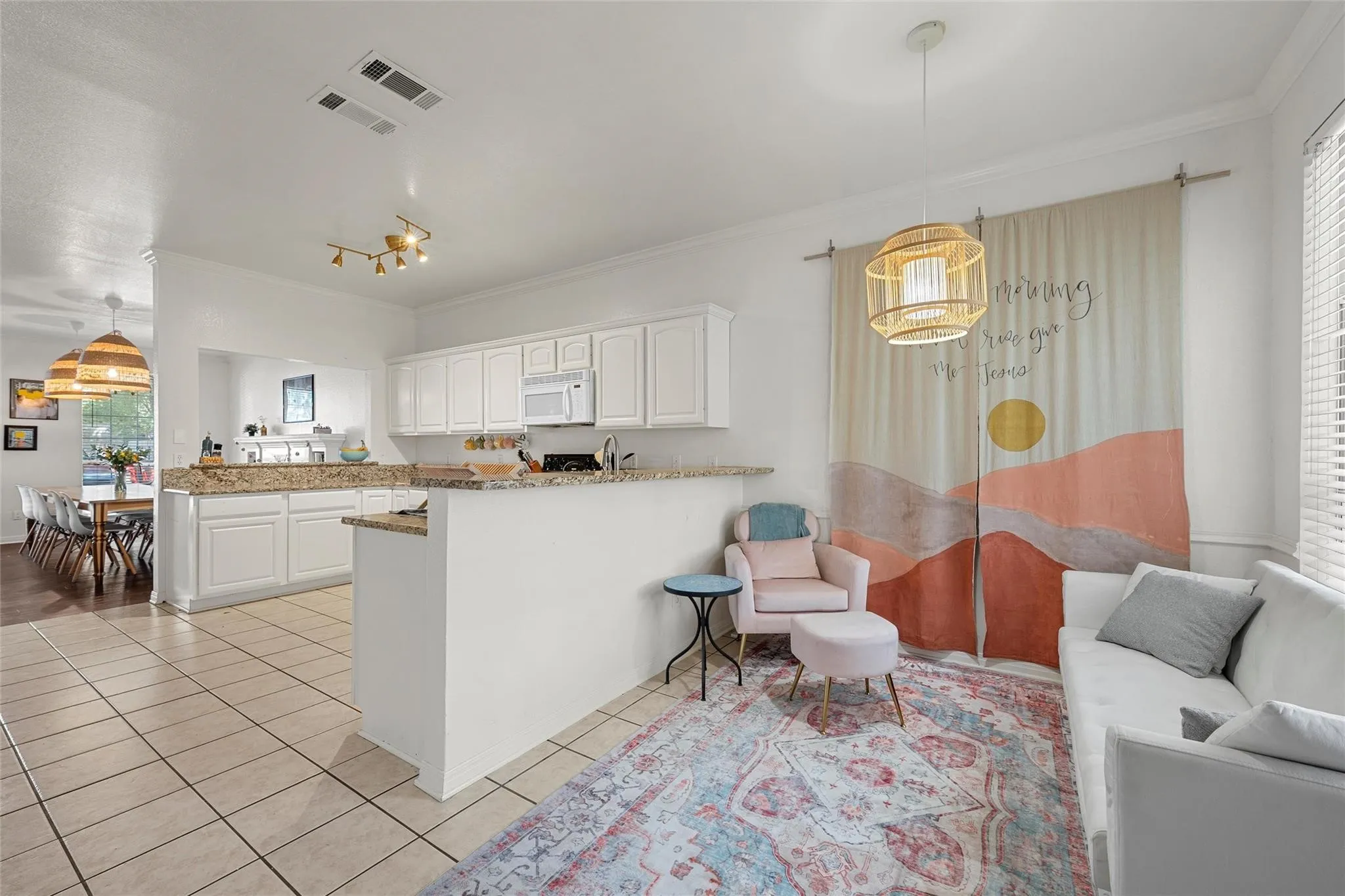 Kitchen with decorative light fixtures, a peninsula, open floor plan, white cabinets, and ornamental molding