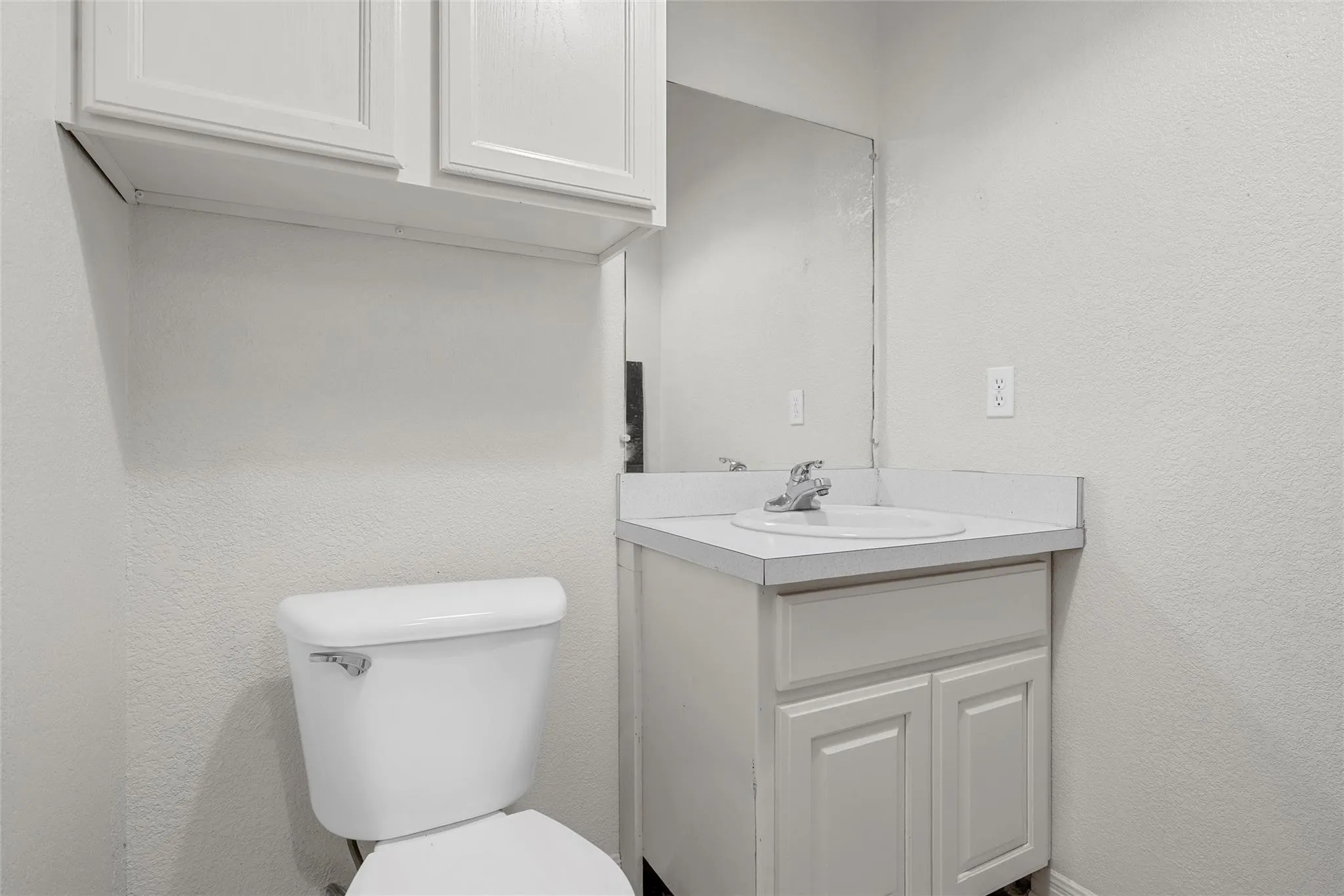 Half bath featuring a textured wall and vanity