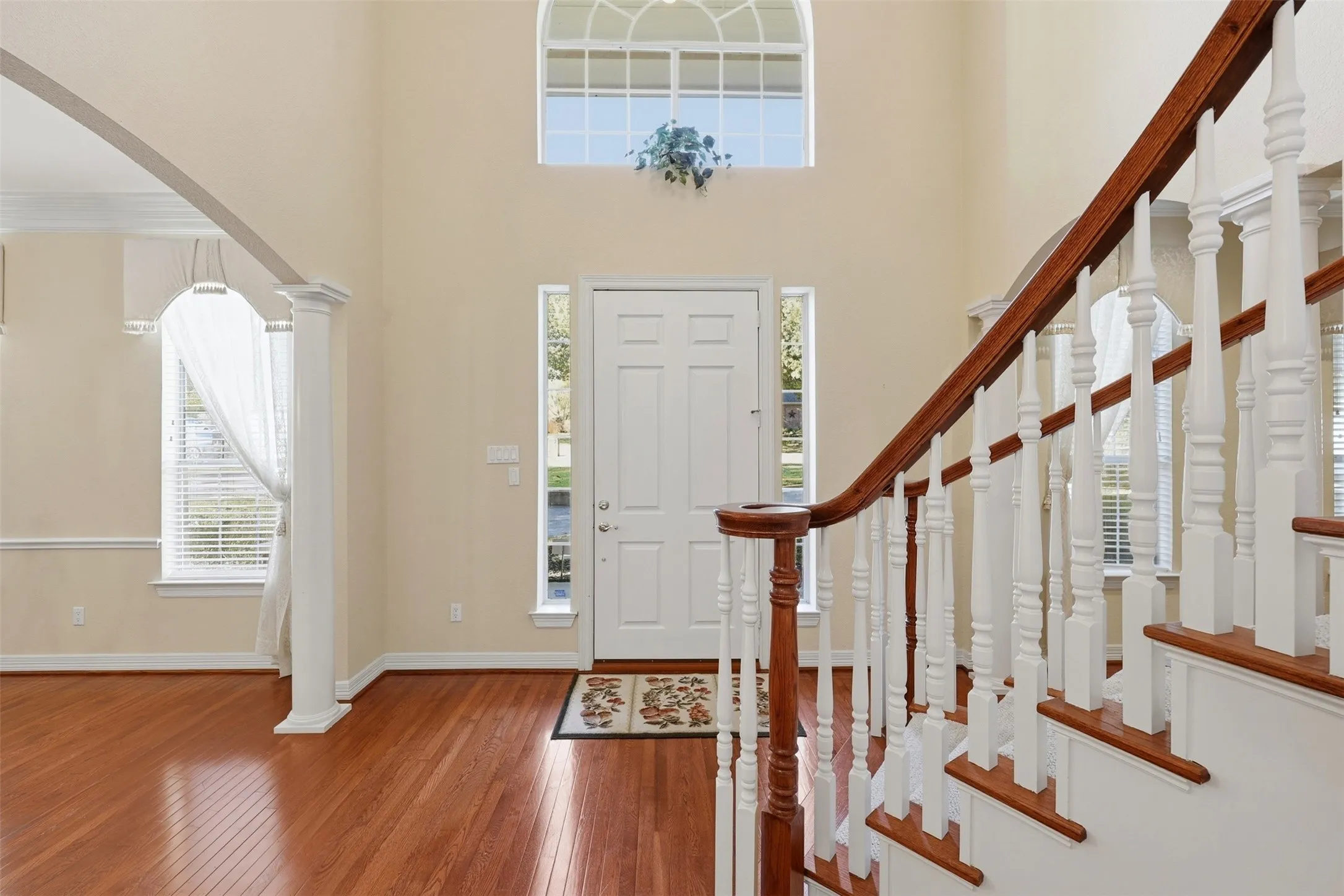 Foyer entrance featuring arched walkways, hardwood / wood-style floors, decorative columns, and a towering ceiling