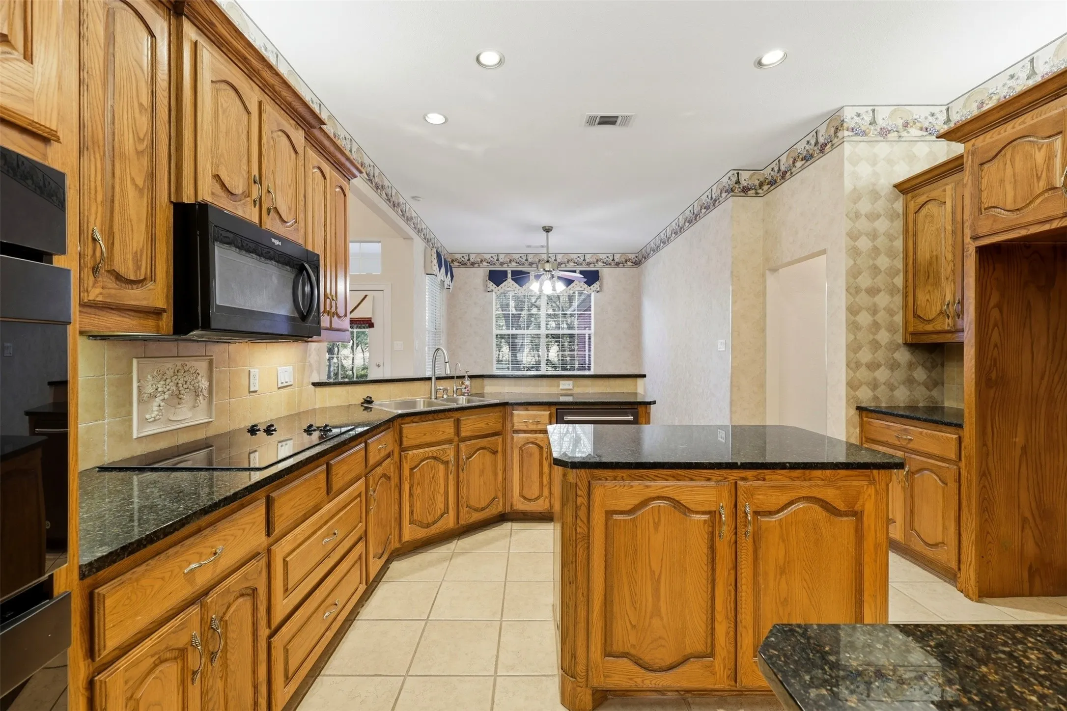 Kitchen with dark stone countertops, a kitchen island, light tile patterned floors, tasteful backsplash, and recessed lighting
