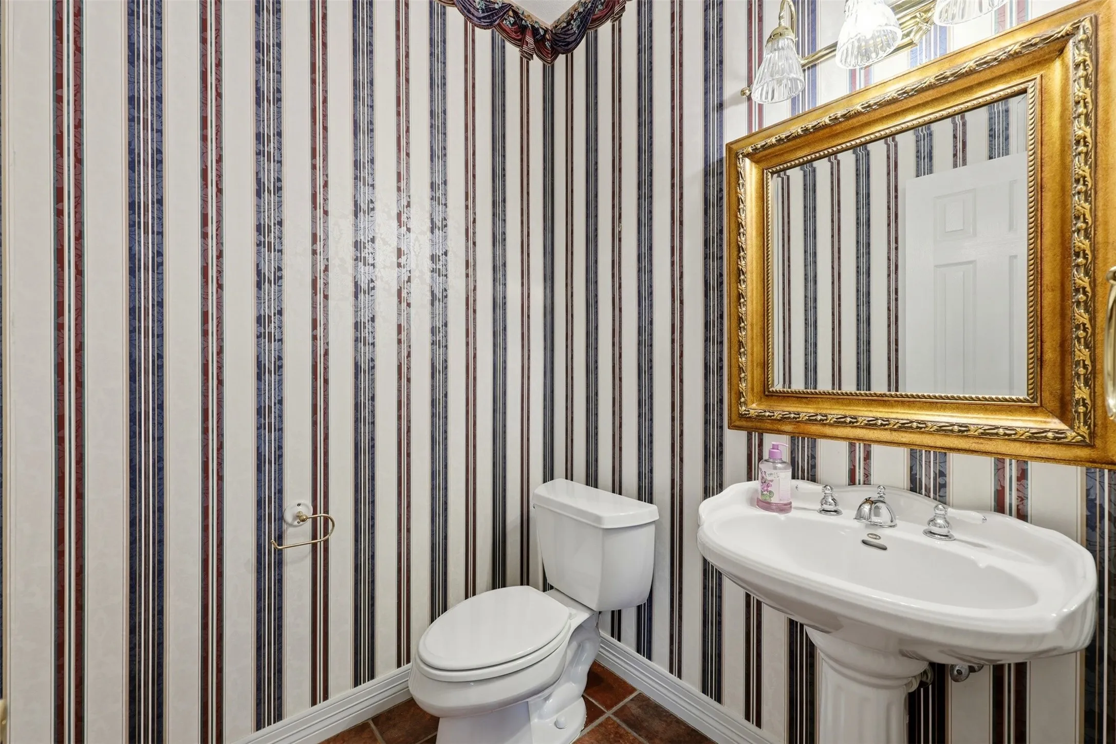 1st floor Half Bathroom with wallpapered walls and dark tile patterned floors