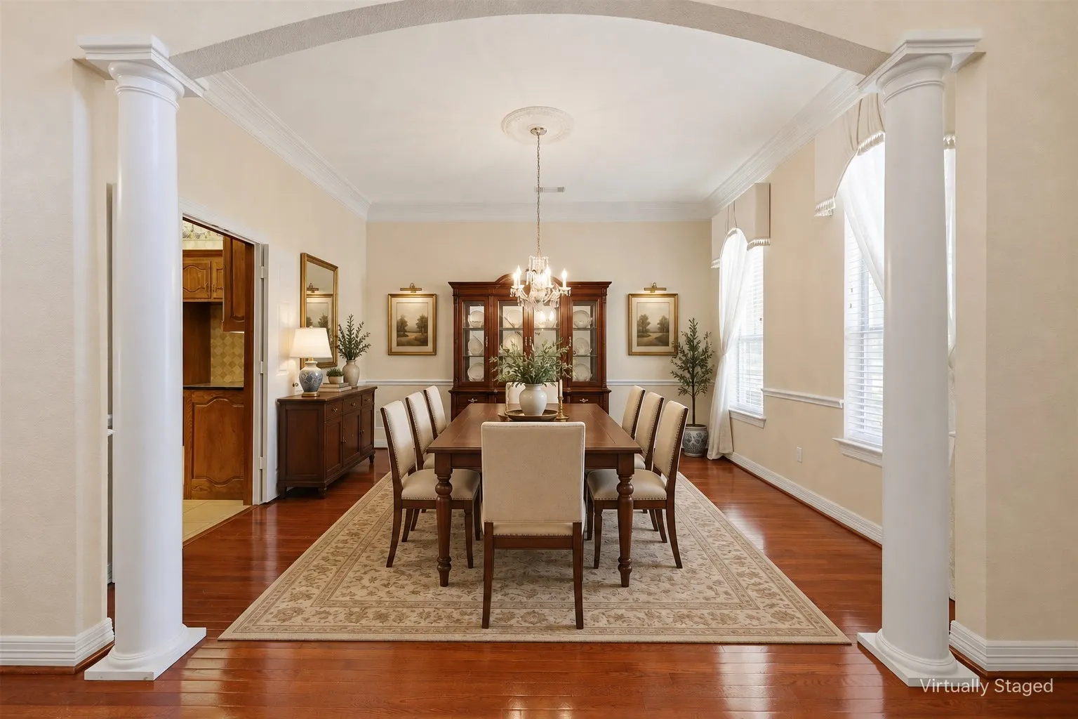 Archway entry with decorative columns, wood-finish flooring, and crown molding
