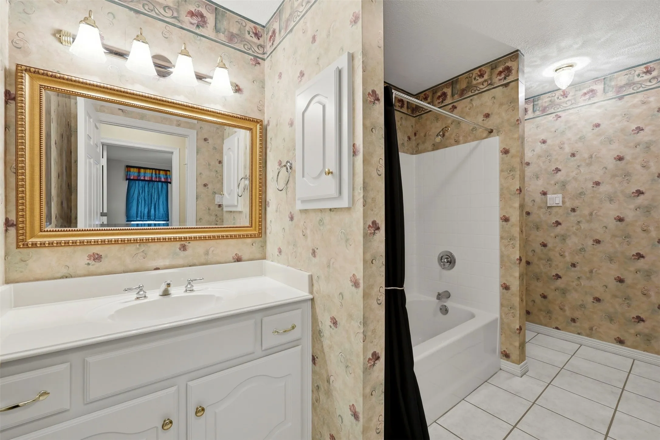 2nd floor Full bath with wallpapered walls, light tile patterned floors, shower / bath combo with shower curtain, and vanity
