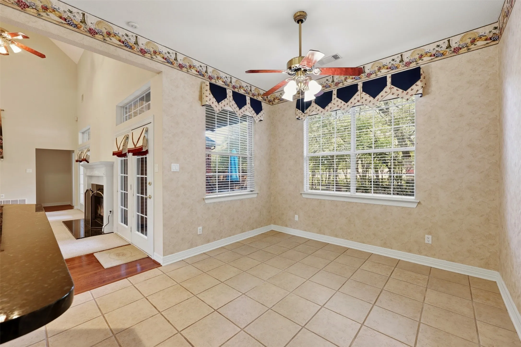 Breakfast area with a ceiling fan, plenty of natural light, light tile patterned flooring, a warm lit fireplace, and wallpapered walls