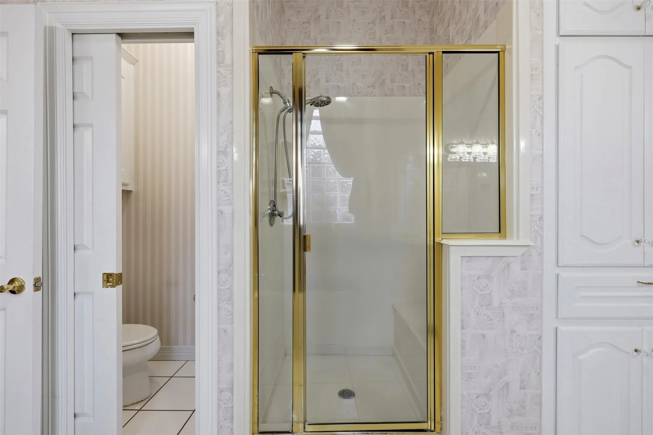 Primary Bathroom with wallpapered walls, a walk-in shower, and toilet closet