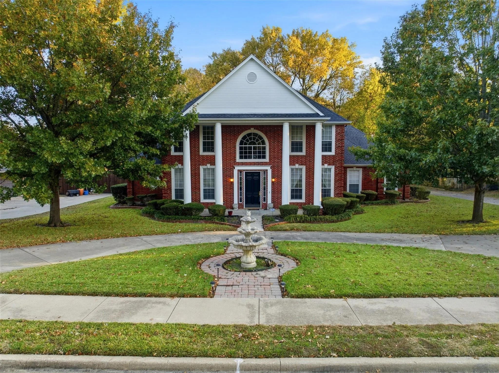 Brick facade residence featuring a prominent portico with four white columns