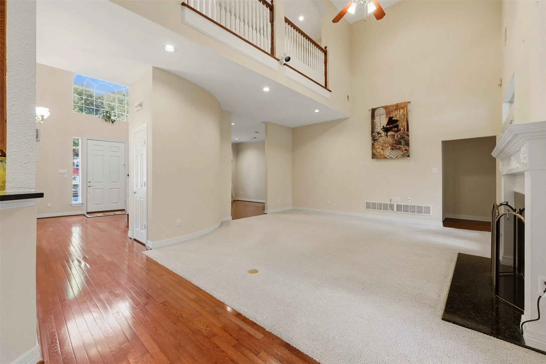 living room with a towering ceiling, light wood finished floors, a fireplace, recessed lighting, and ceiling fan
