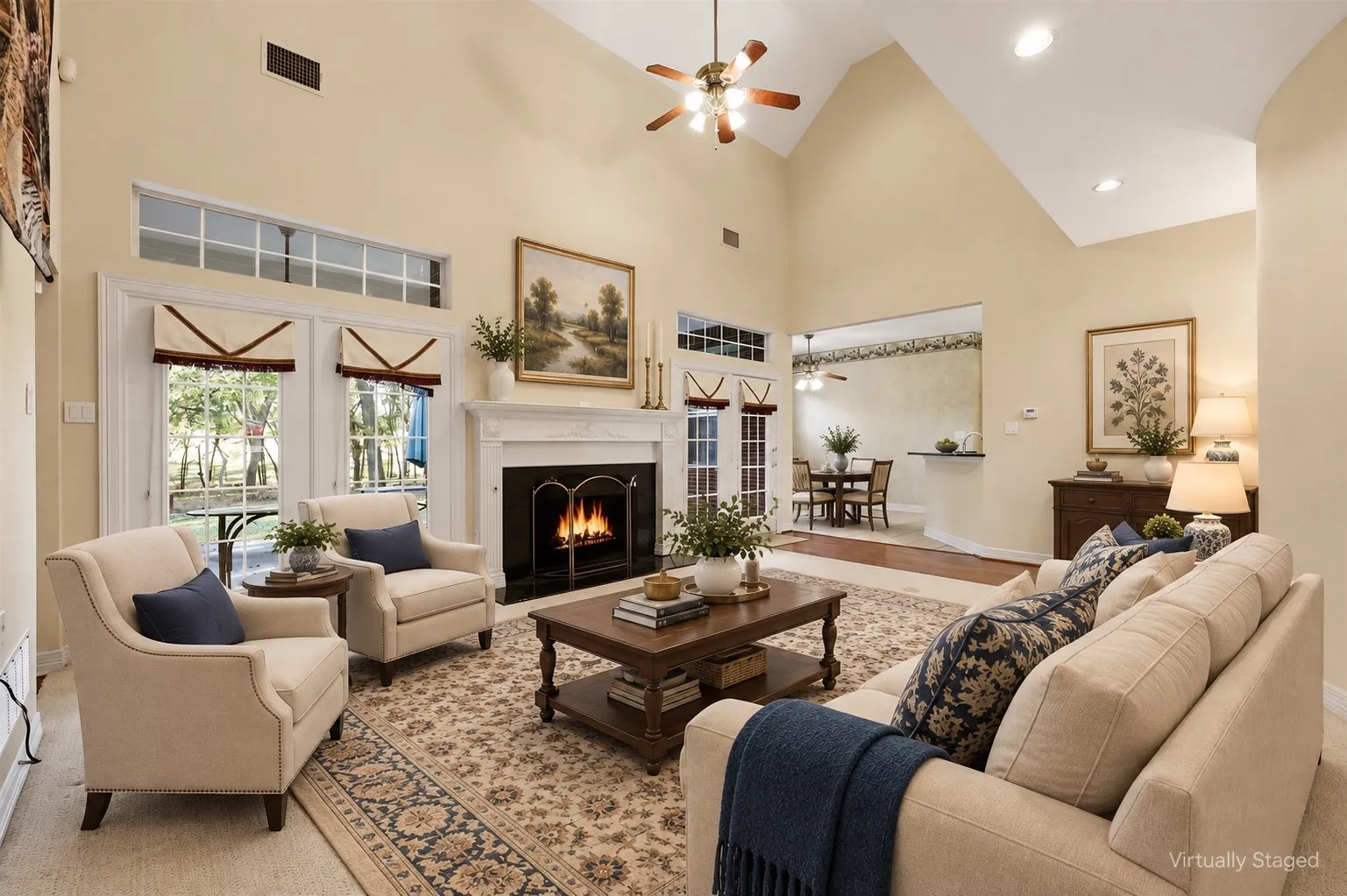 Vaulted ceiling with a ceiling fan, fireplace with mantel, French doors with transom windows, and recessed lighting
