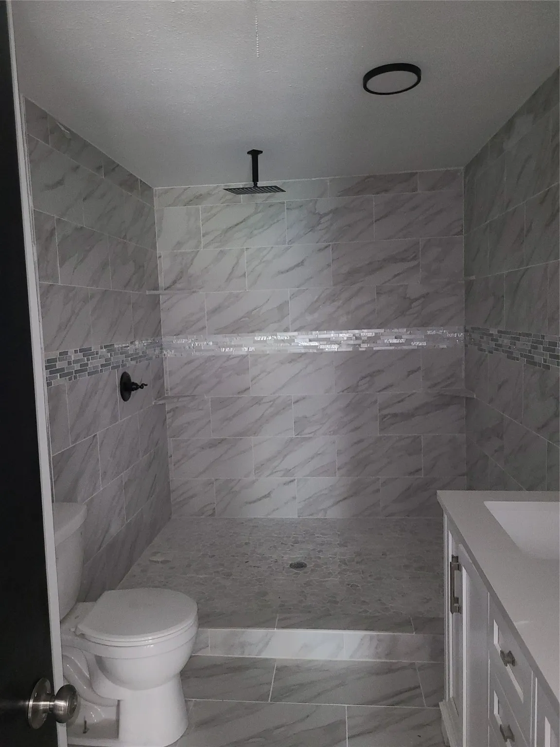 Bathroom with tile walls, a tile shower, and vanity