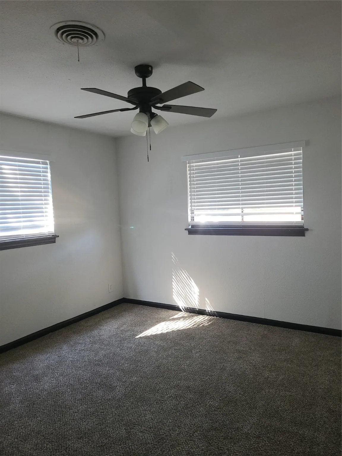 Empty room featuring healthy amount of natural light, carpet flooring, and ceiling fan