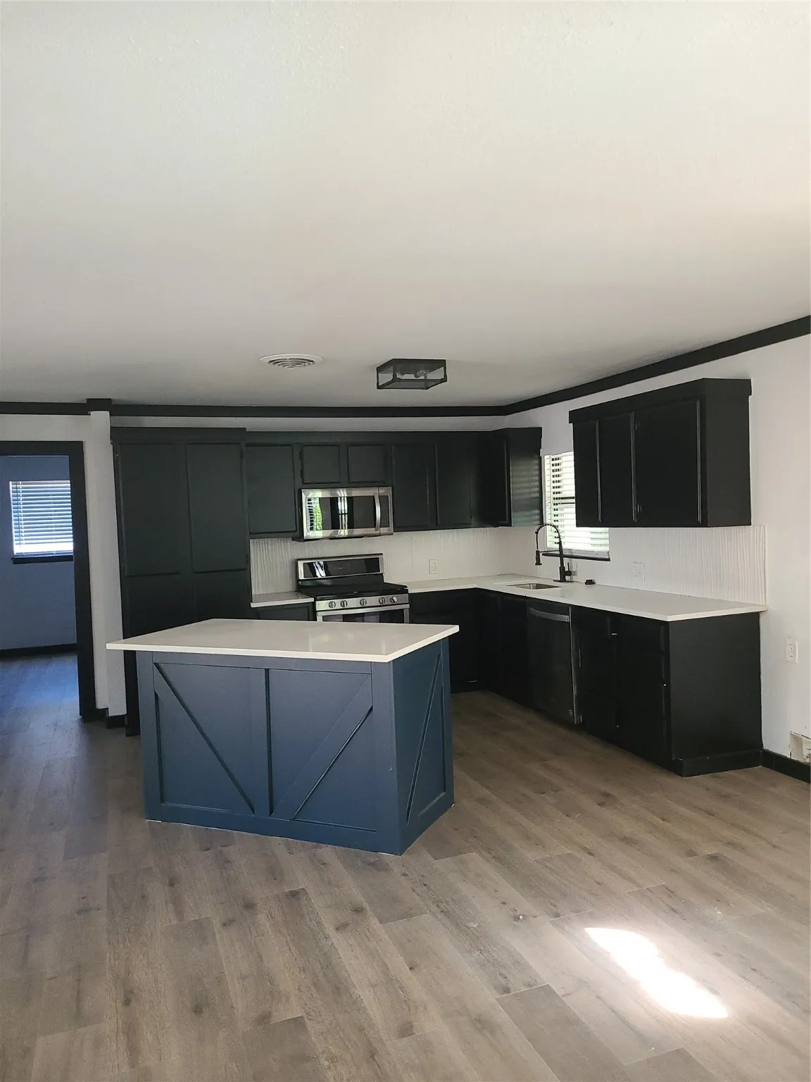 Kitchen featuring dark cabinetry, stainless steel range oven, a center island, light wood-style flooring, and black microwave