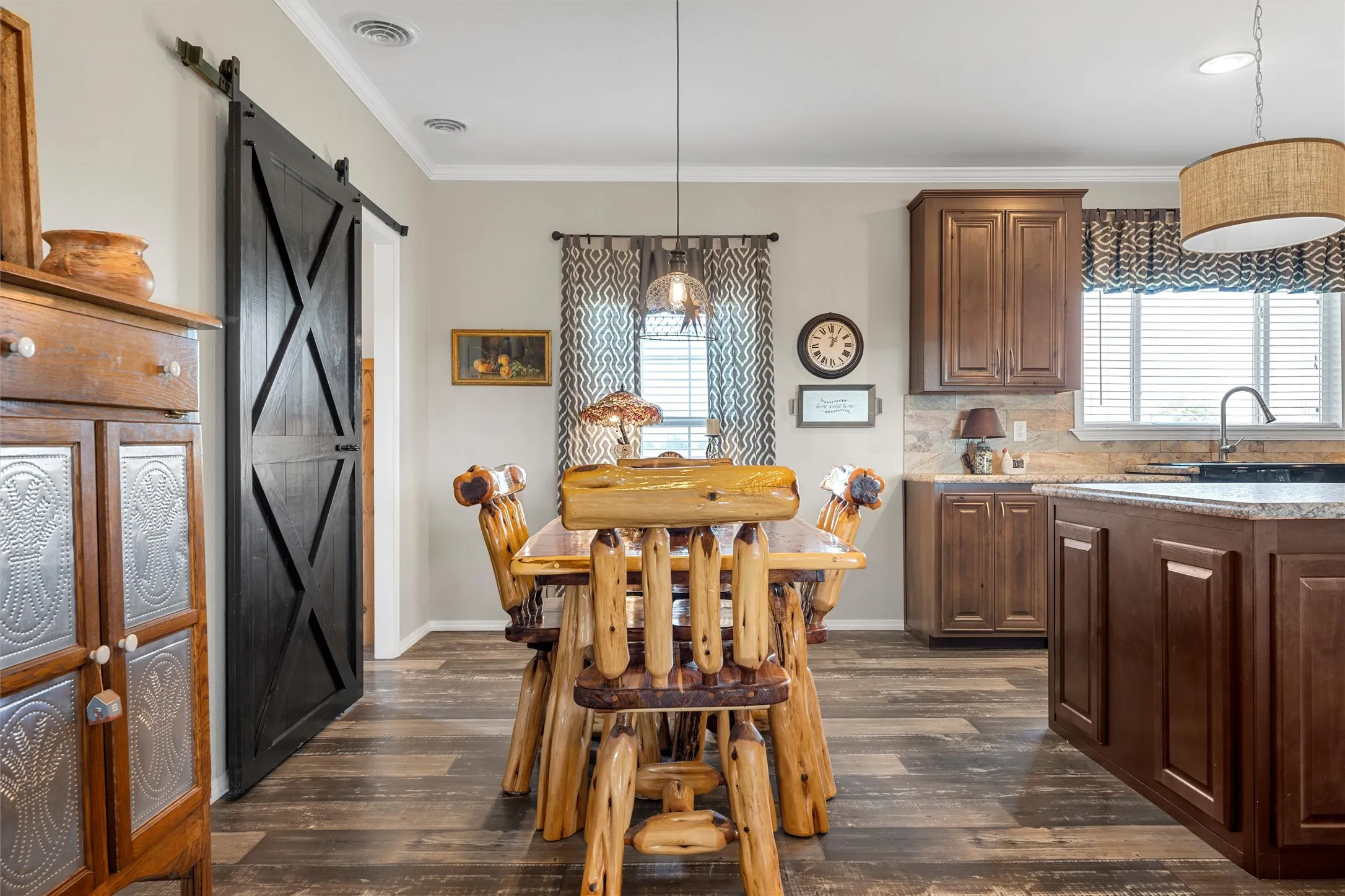 Dining room featuring healthy amount of natural light, dark wood-type flooring, crown molding, and a barn door