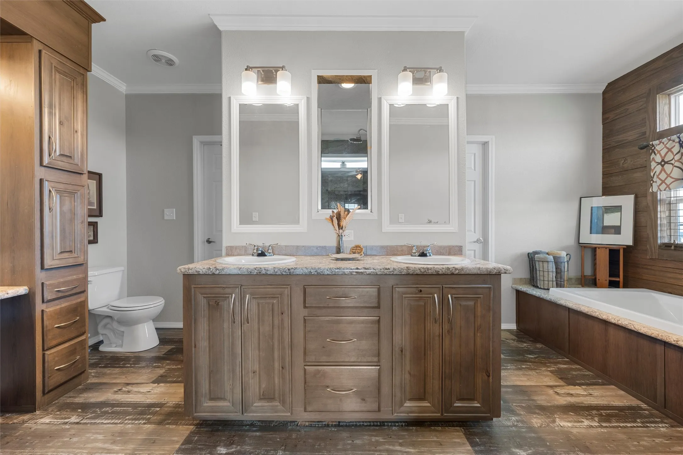 Full bathroom with double vanity, dark wood-style floors, a garden tub, ornamental molding, and wooden walls