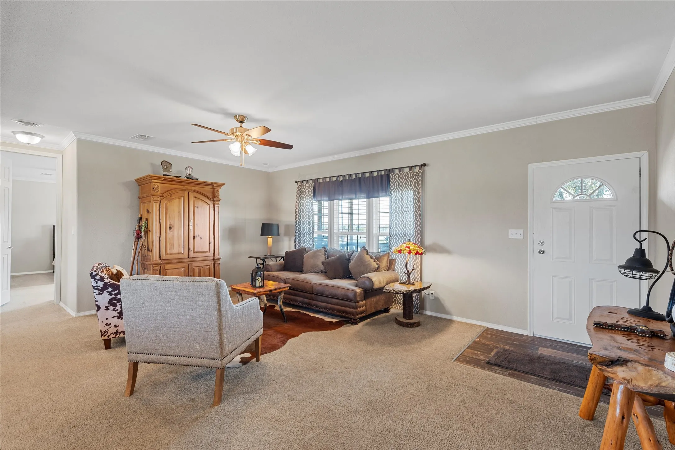 Carpeted living area with crown molding and a ceiling fan