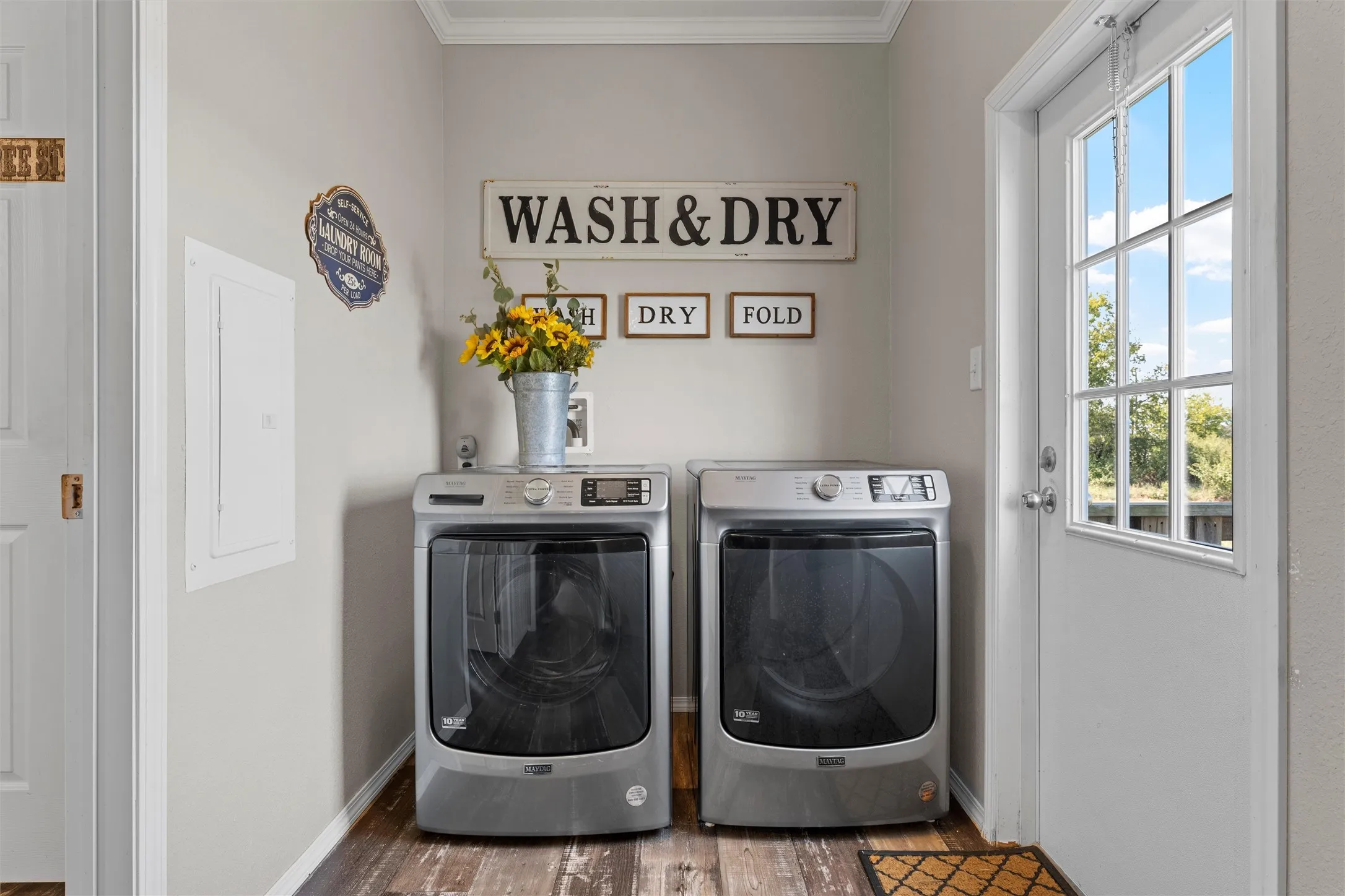 Laundry area featuring electric panel, washer and clothes dryer, wood finished floors, and ornamental molding