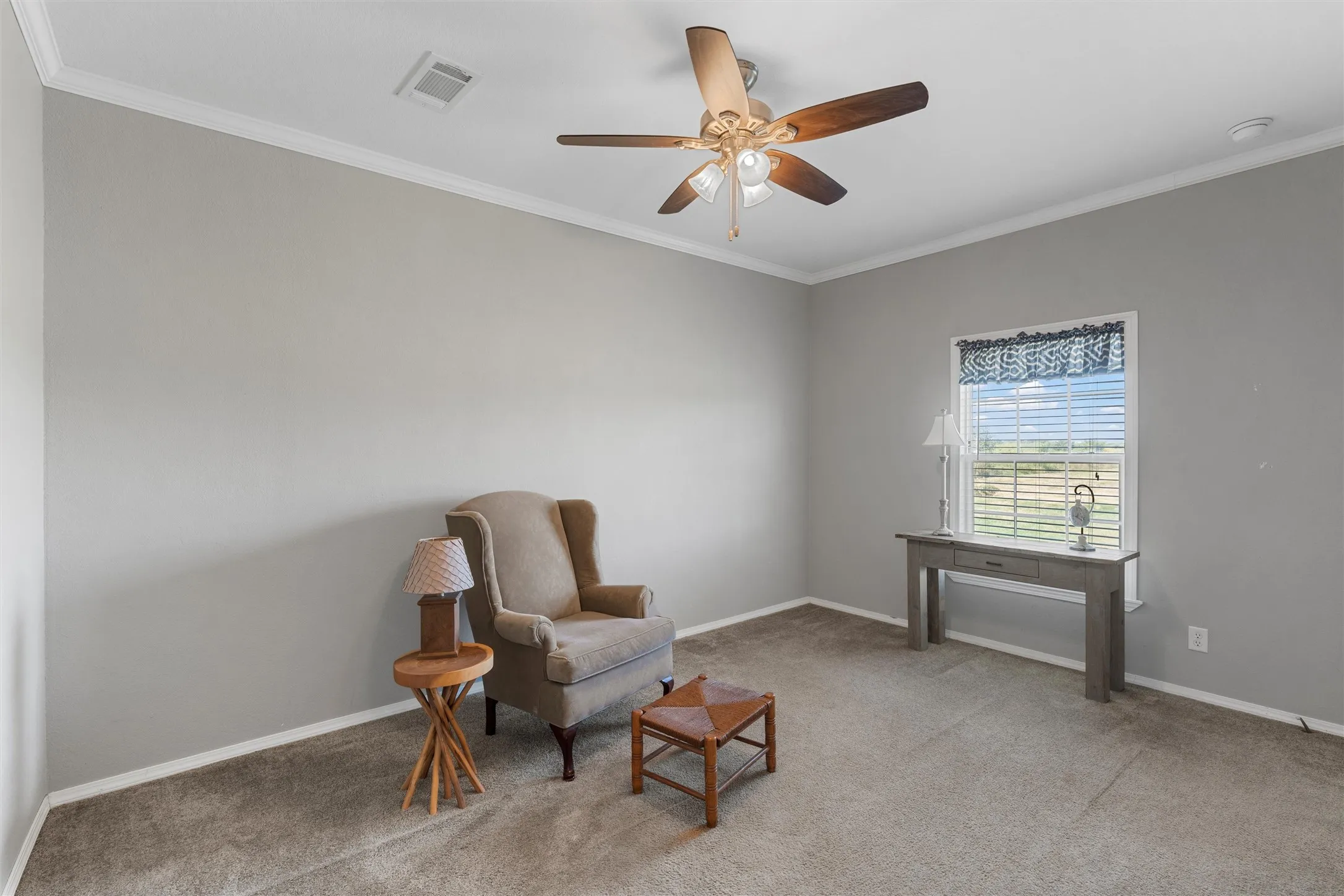 Living area with ornamental molding, light carpet, and a ceiling fan