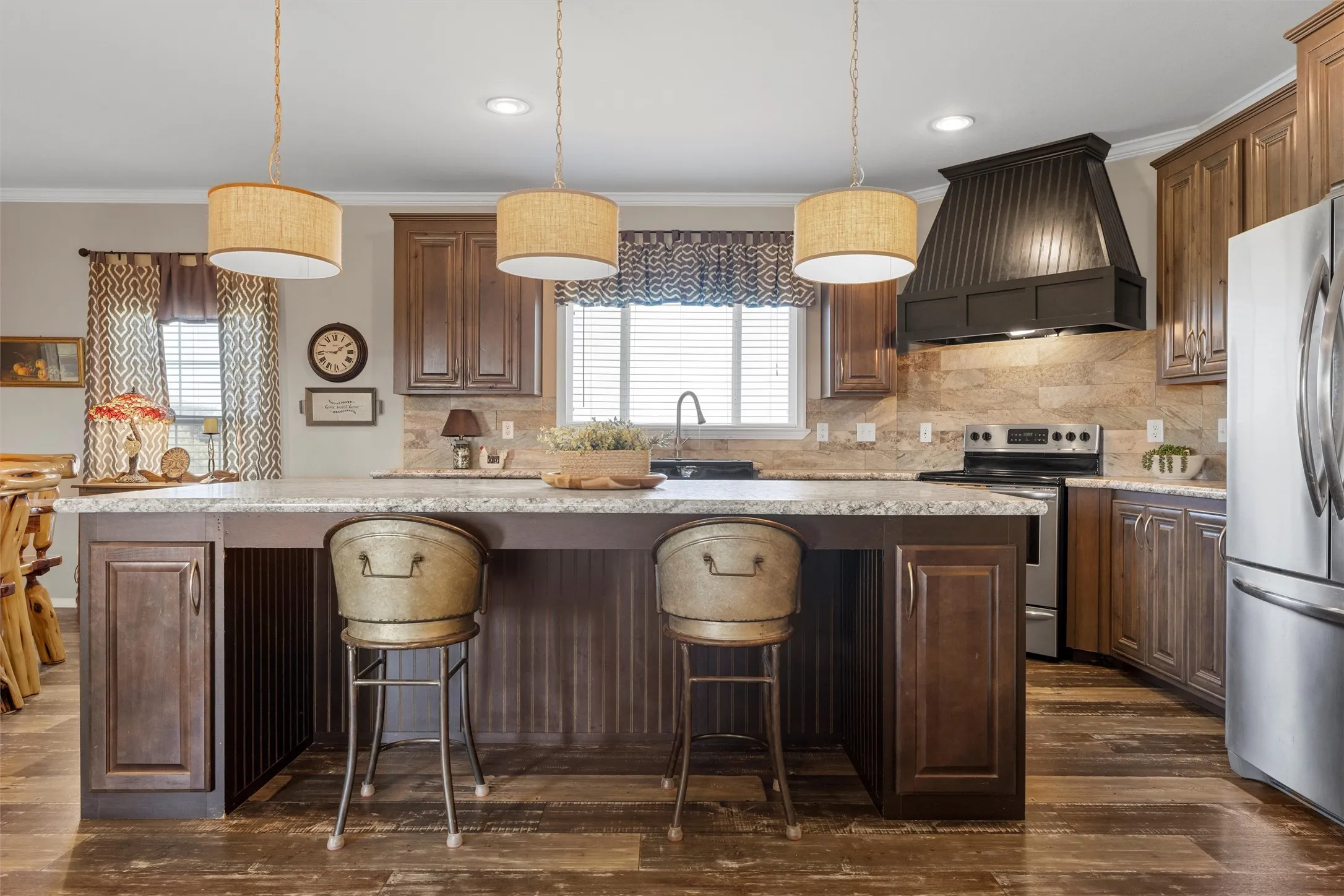 Kitchen with decorative backsplash, a center island, custom range hood, ornamental molding, and appliances with stainless steel finishes