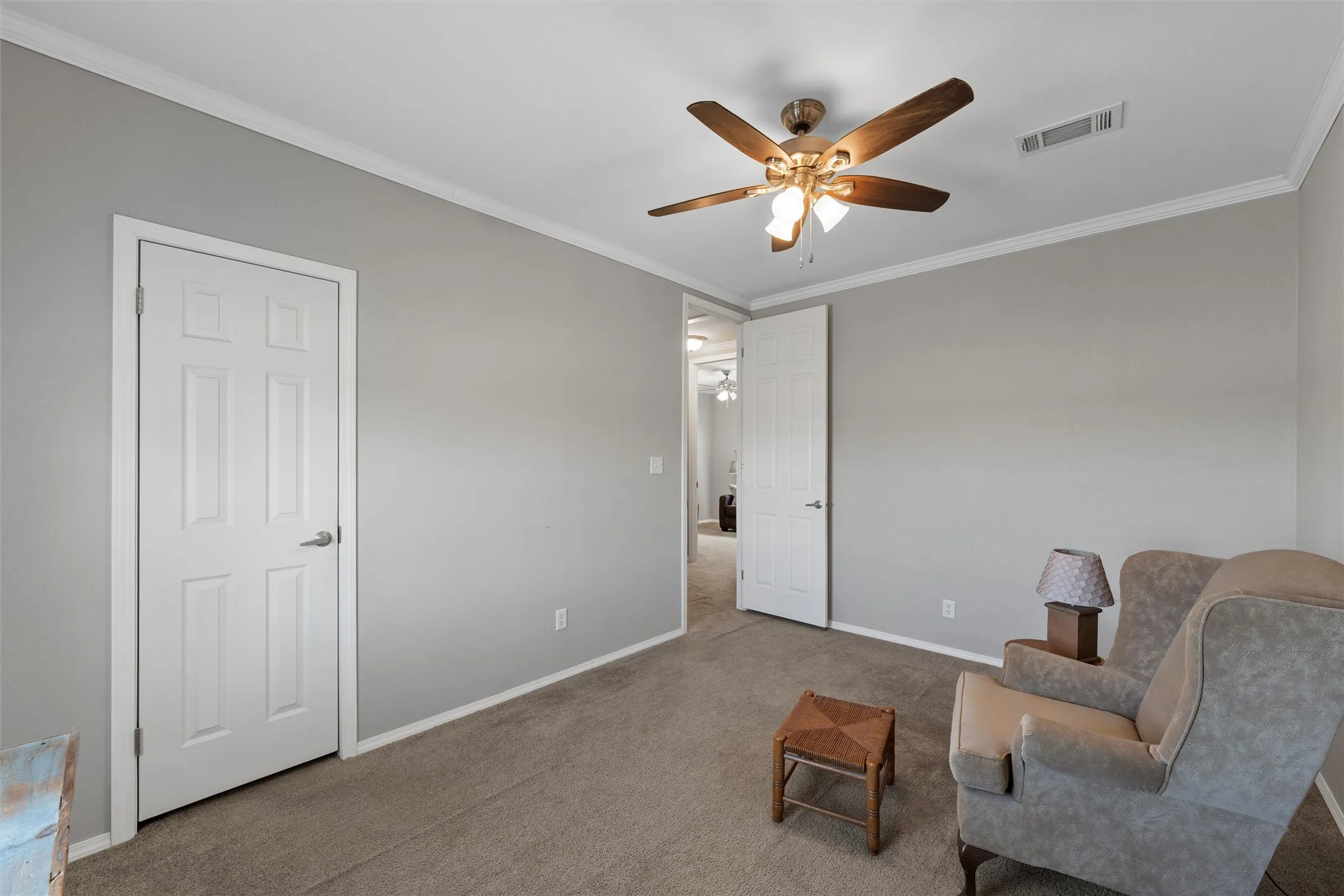 Living area with crown molding, carpet floors, and a ceiling fan