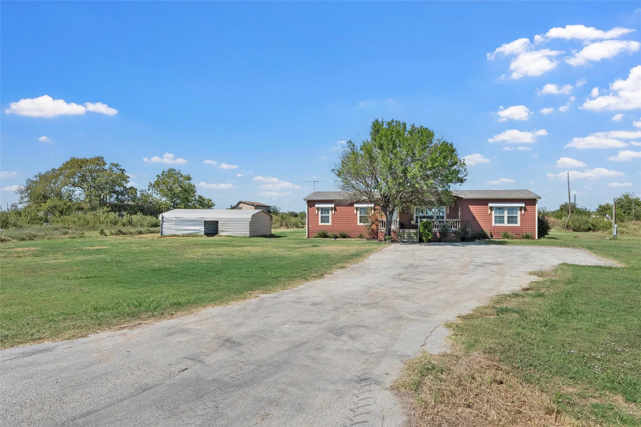 Ranch-style house with a front lawn, driveway, and an outdoor structure