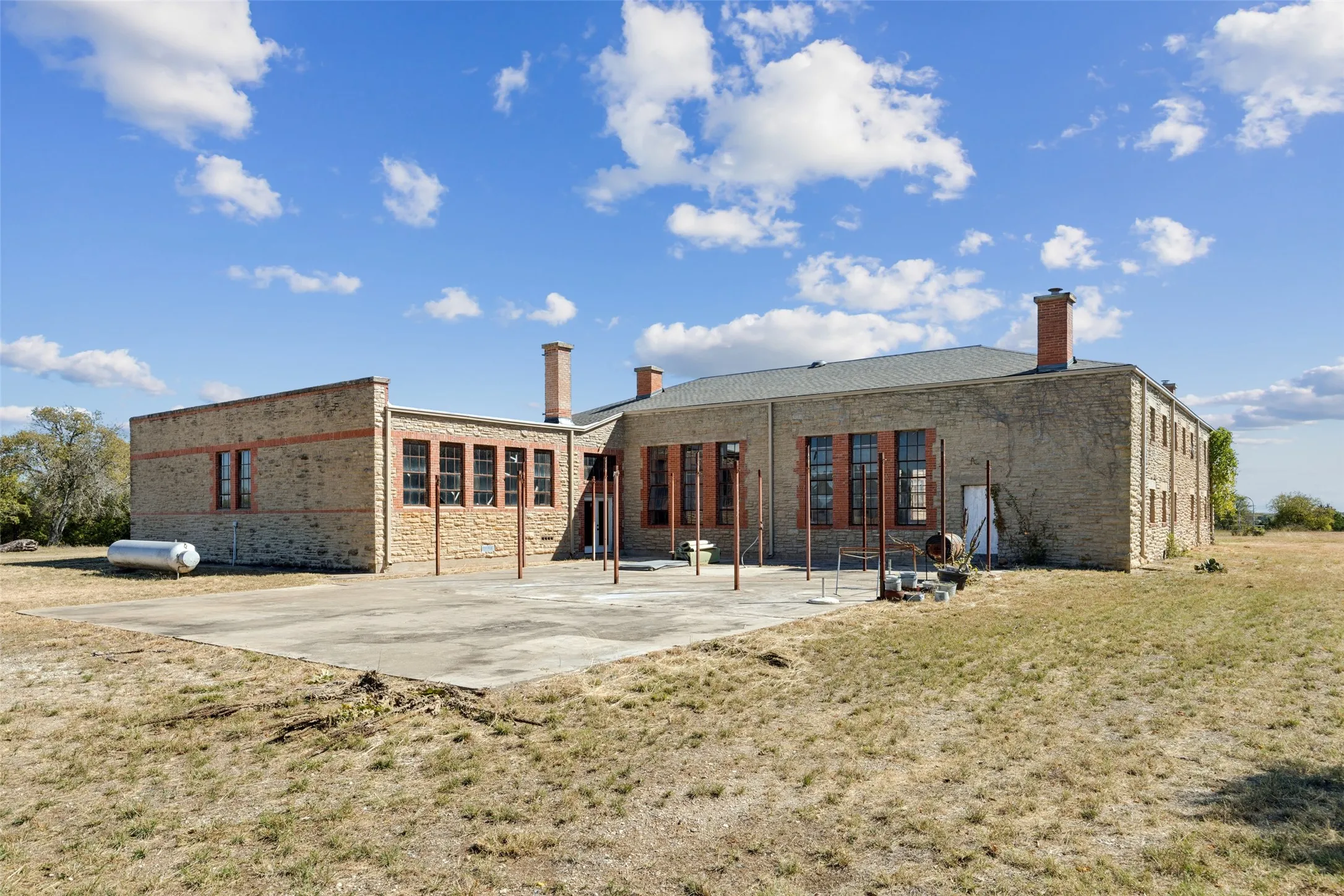 Rear view of property featuring brick siding, a yard, a patio area, and a chimney