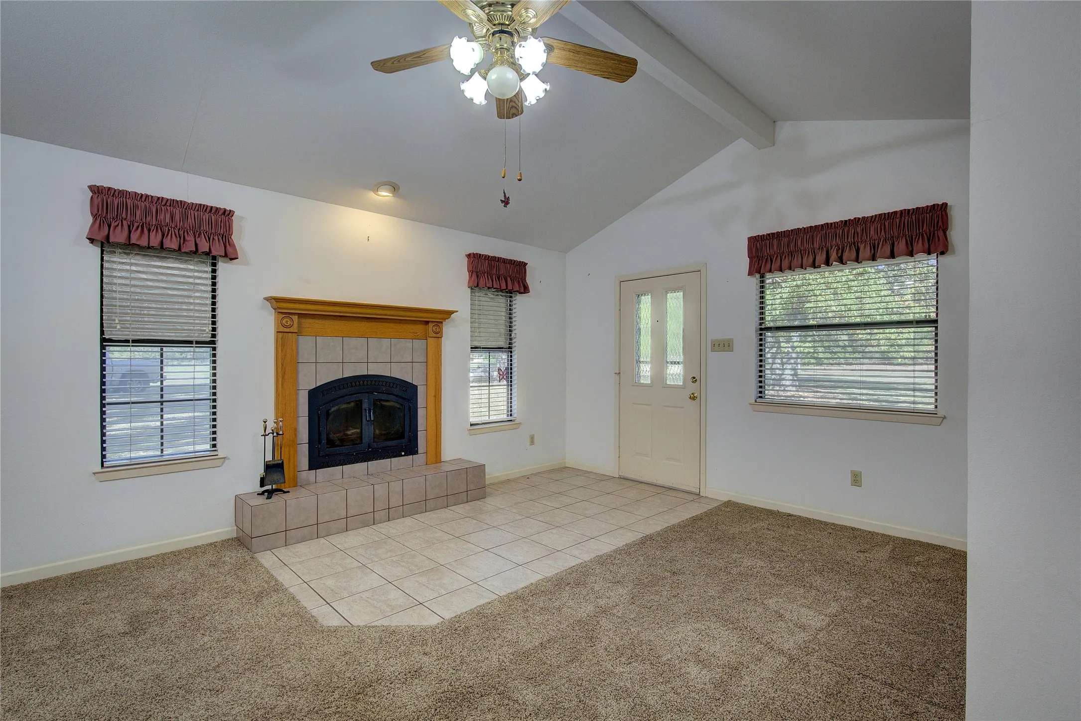 Front entry is tiled and opens to living room with vaulted ceiling and wood-burning tiled fireplace.