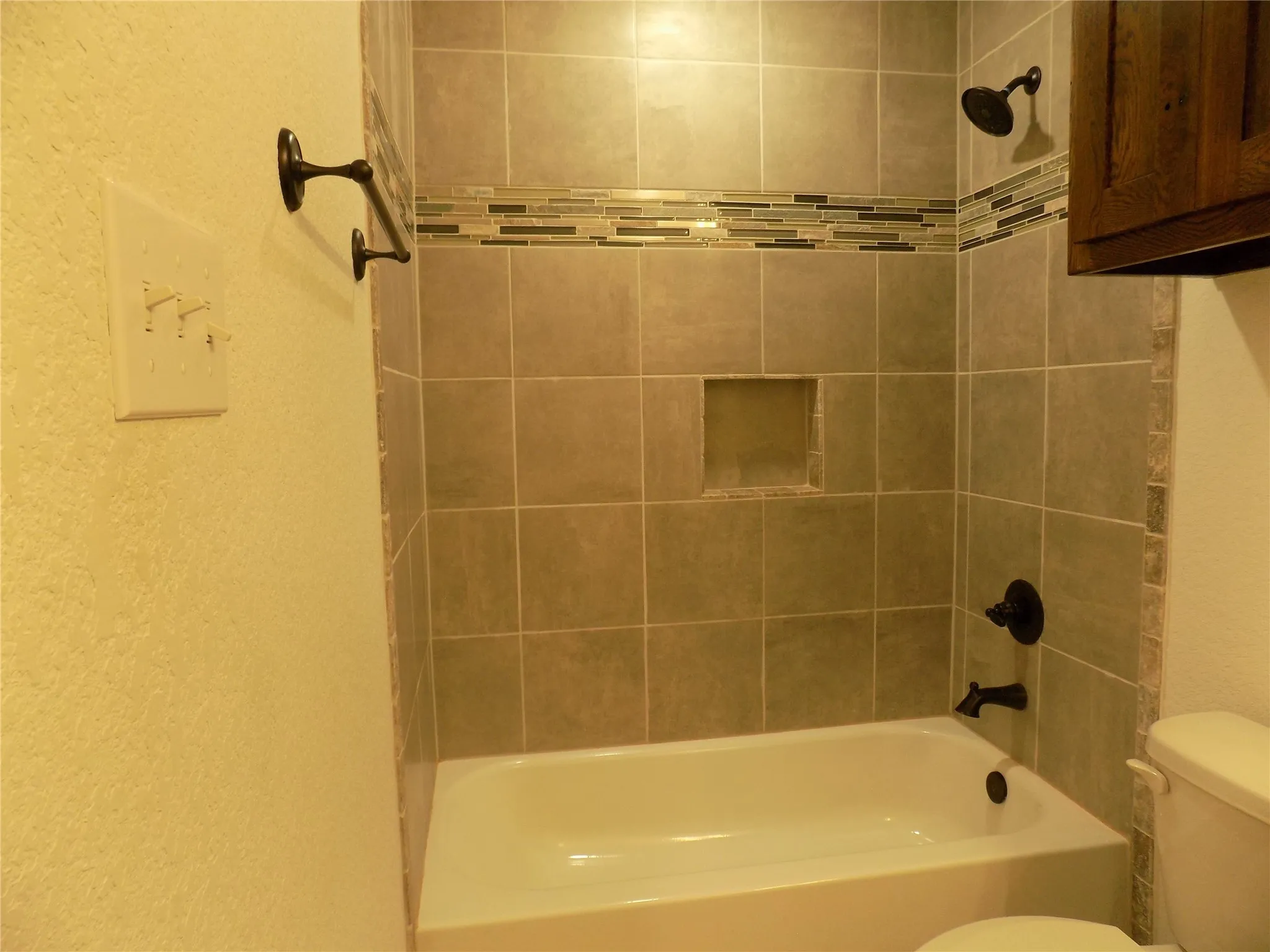 Closer view of tiled bath tub and shower in guest bath