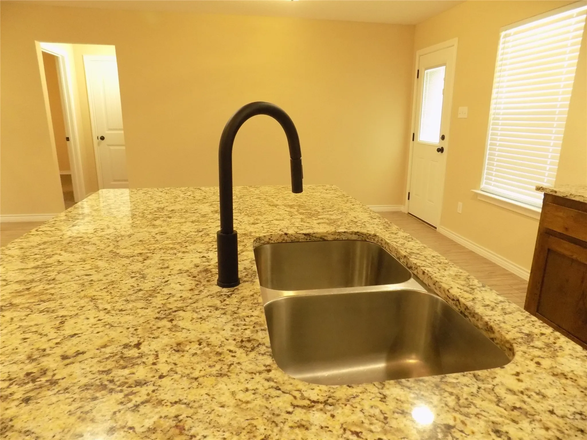 Closer view of under cabinet stainless steel sink and granite counter top; eat in kitchen island