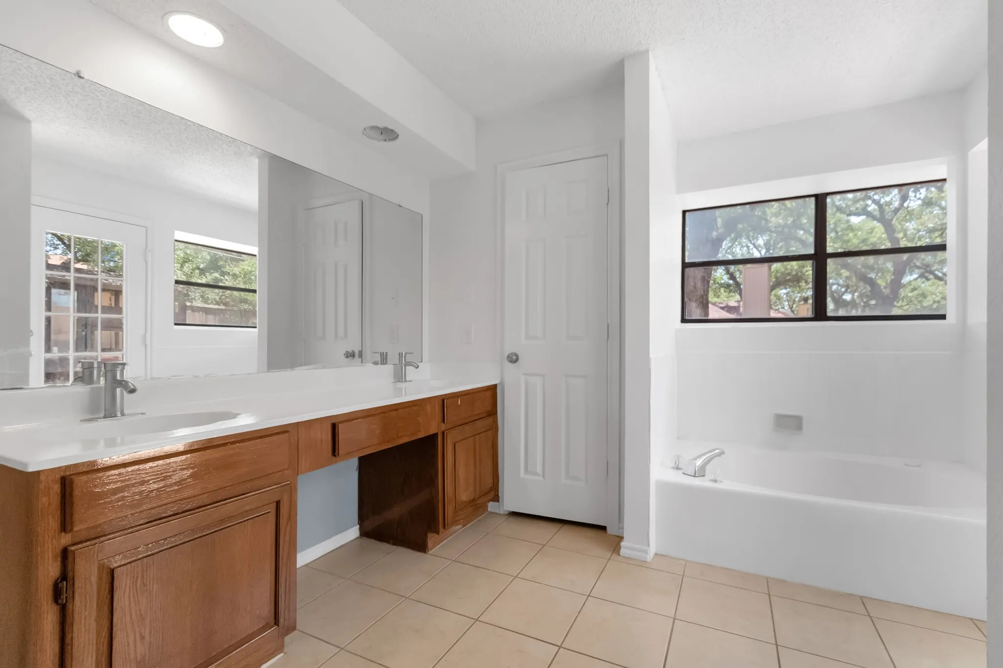 Dual vanity with integrated sinks, a built-in makeup area, and wood-finish cabinetry