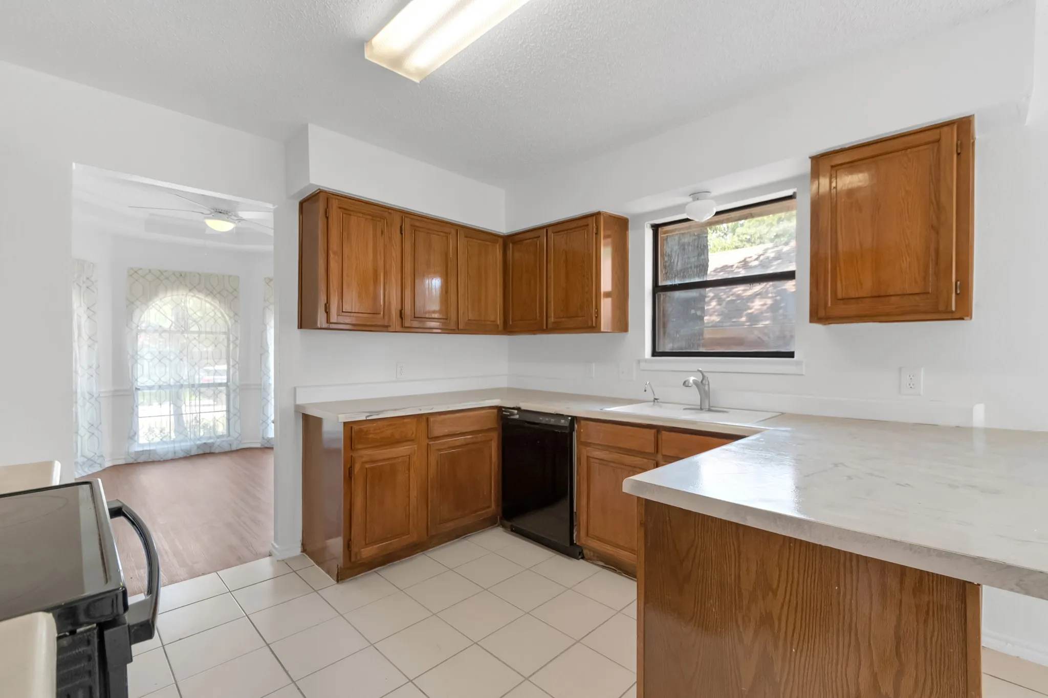Kitchen featuring wood cabinetry, light-toned countertops, and tile flooring