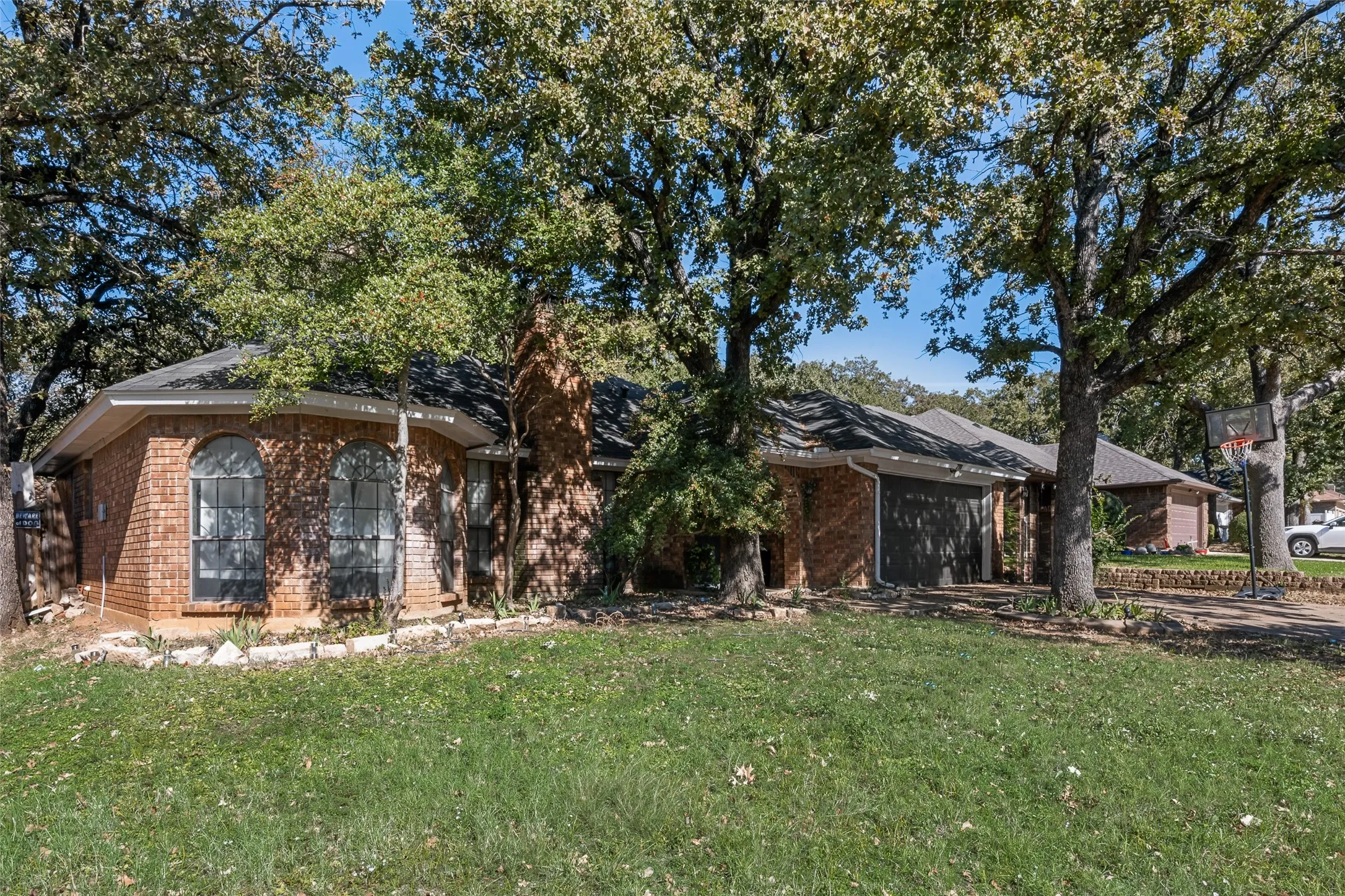 View of front facade with a front lawn, brick siding, an attached garage, and driveway