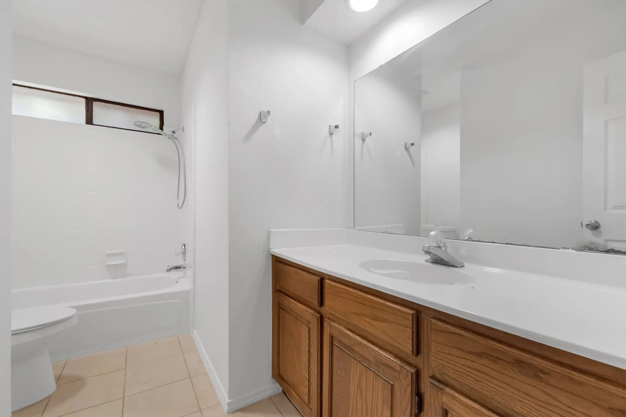Spa-inspired bathroom featuring a wood-finish vanity with dual sinks, white quartz countertop, and polished chrome fixtures