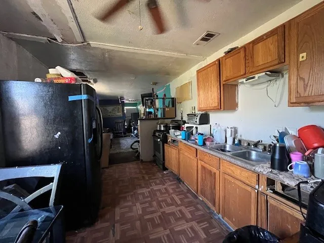 Kitchen with freestanding refrigerator, brown cabinets, stainless steel range oven, a ceiling fan, and open floor plan
