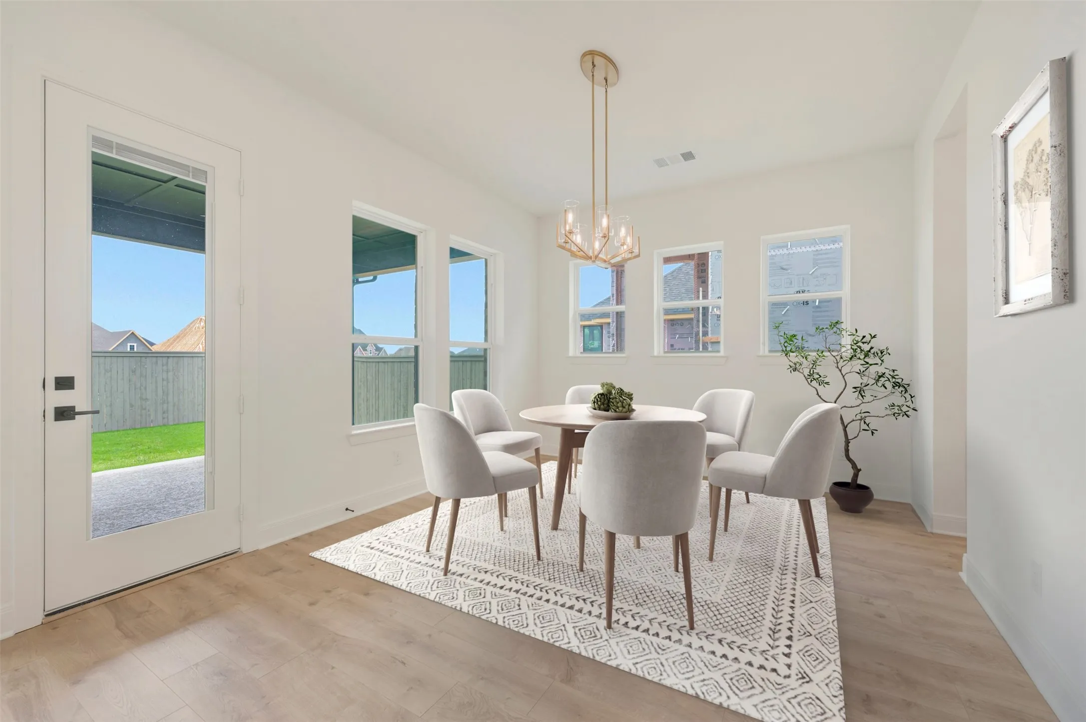 Bright dining area featuring wood-finish flooring, multiple windows, a full-light glass door, and a contemporary gold-tone chandelier