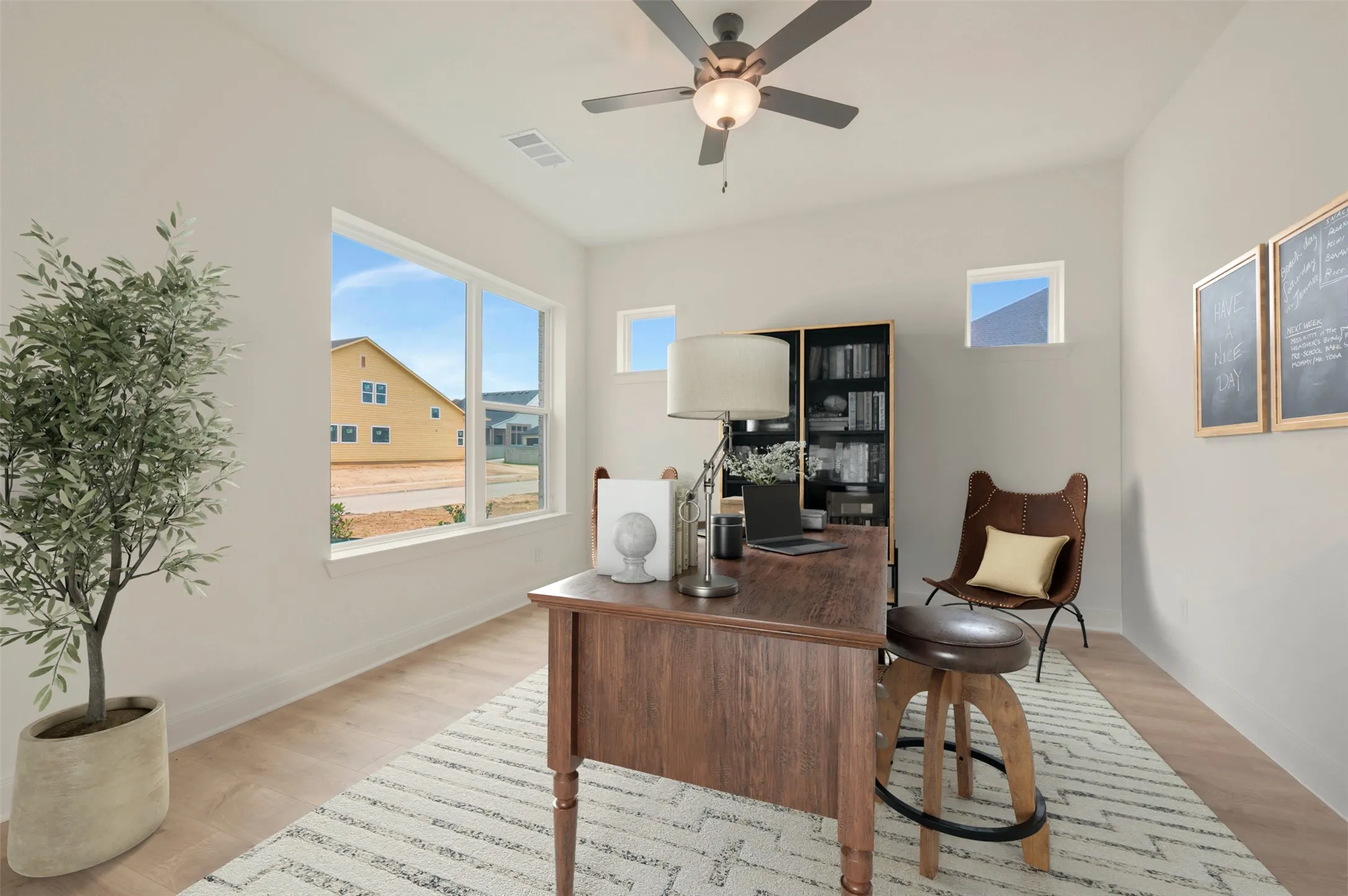 Bright interior space featuring light wood-finish flooring, a contemporary ceiling fan with integrated lighting, and multiple windows