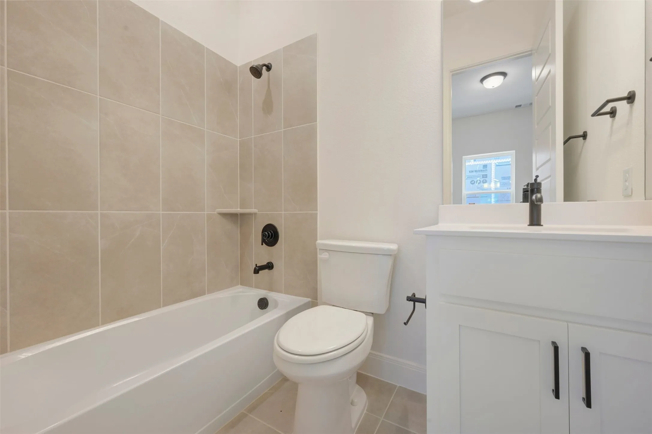 Bathroom featuring a white bathtub, light-toned tile surround with a built-in niche, and matte black plumbing fixtures