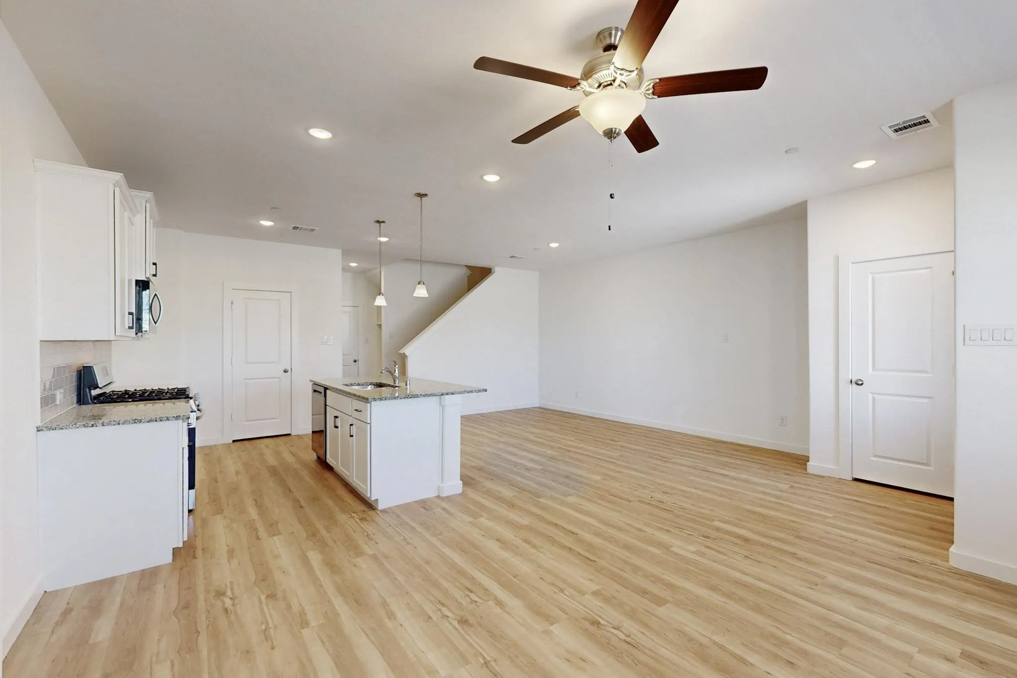 Kitchen featuring white cabinets, recessed lighting, light stone countertops, and decorative light fixtures