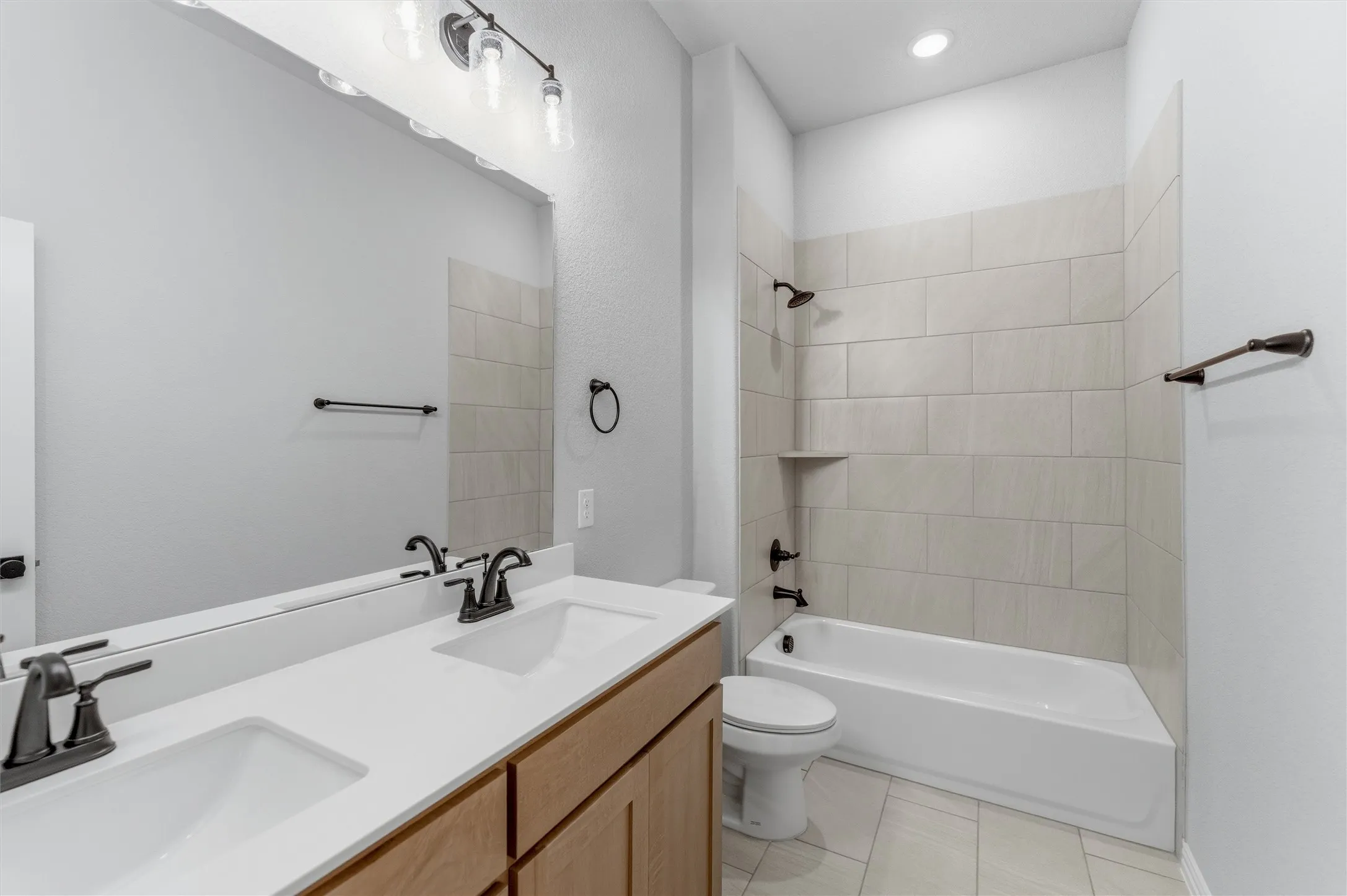 Bathroom with double vanity, shower / washtub combination, light tile patterned floors, and recessed lighting