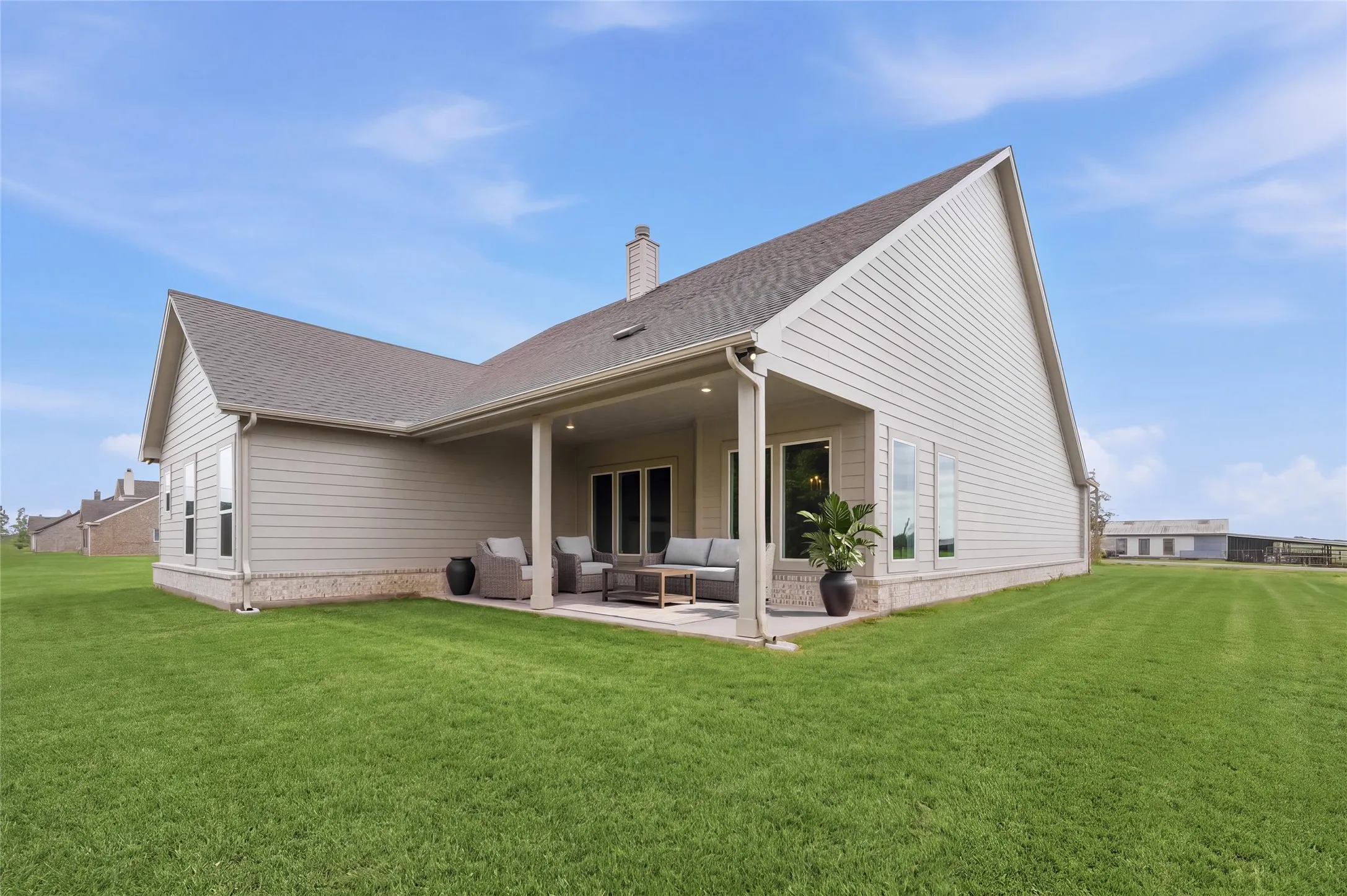 Expansive backyard with a covered patio, featuring a gabled roofline and siding exterior