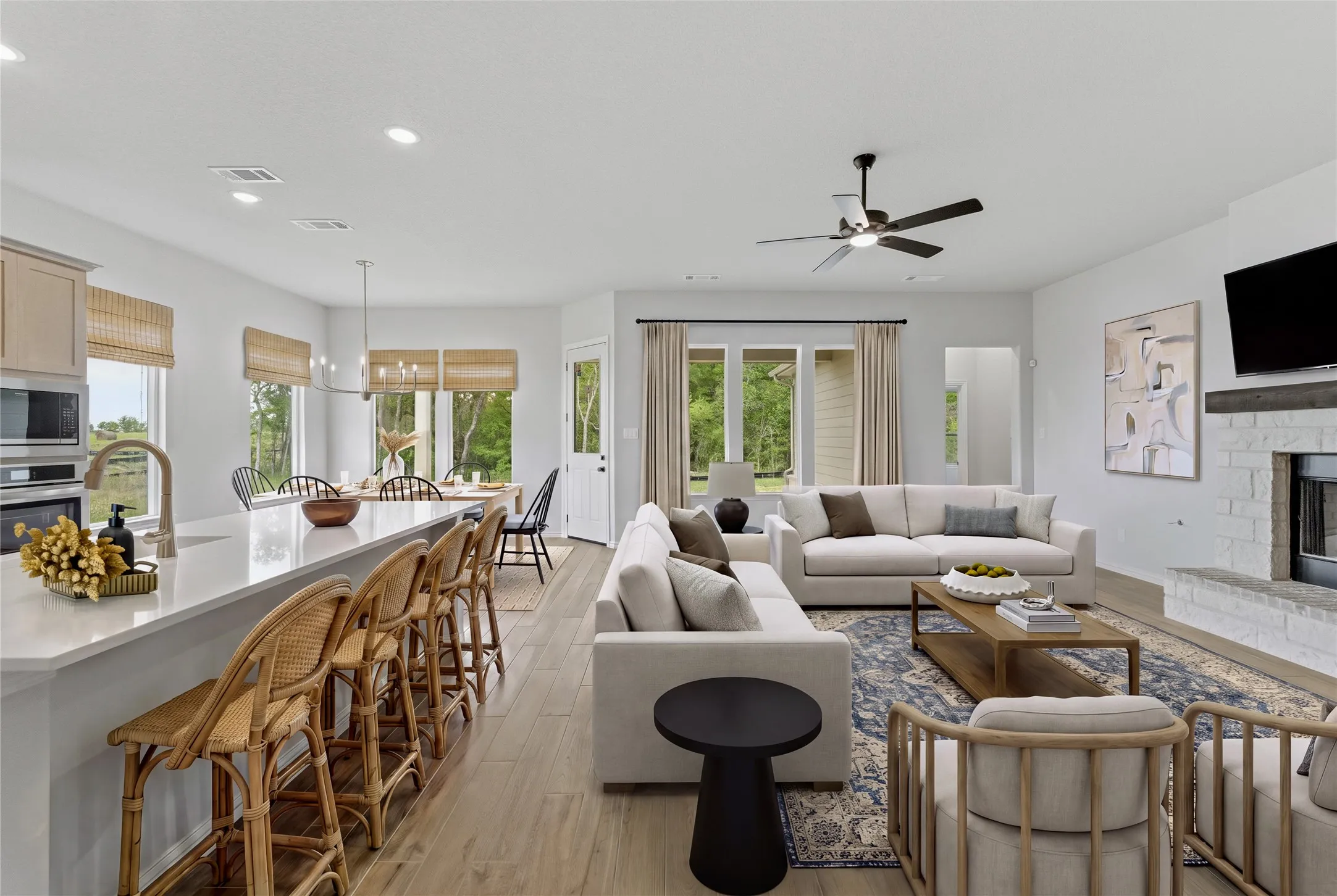 Open-concept living area with wood-finish flooring, a white brick fireplace, and recessed lighting