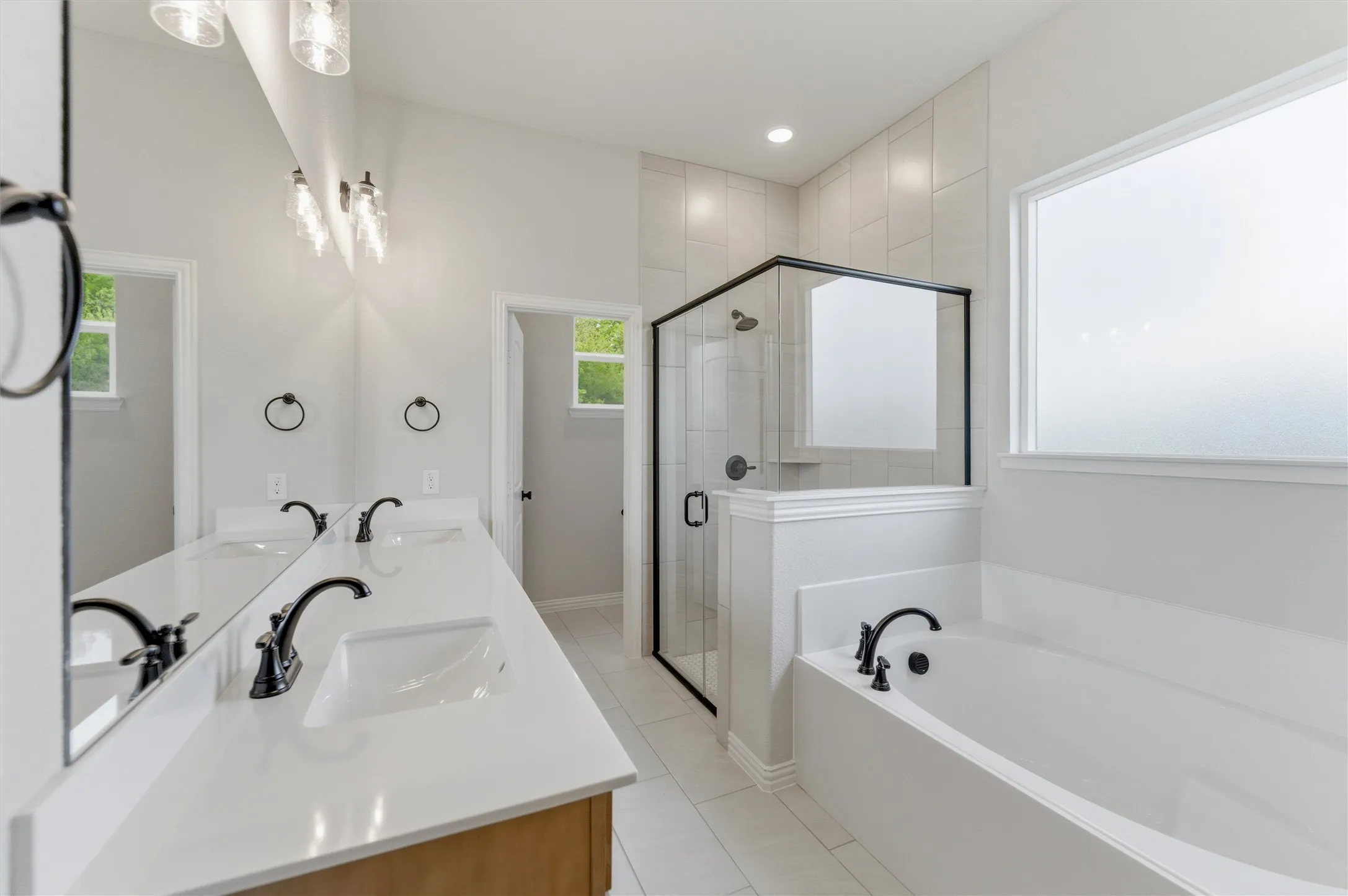 Full bath with double vanity, a stall shower, a bath, light tile patterned floors, and recessed lighting